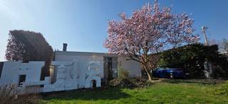 <em>Wie Katrien Wouters zegt, zegt vastgoed met een tikkeltje meer. En dat is niet zomaar.<br /><br />Deze brutalistisch-modernistische woning belichaamt het samenspel van architectonische finesse en eigentijdse leefkwaliteit. Het ontwerp is afkomstig van de hand van architect Adolf Nivelle, in co-creatie met de bouwheer, kunstenaar Toon Vanmechelen.</em><br /><br />Hier geen overdaad: zichtbaar beton, baksteen en hout tonen eerlijk hun structuur. Deze architectuur sluit aan bij een internationale beweging die eenvoud en functionaliteit benadrukt. Elk detail is doordacht, elke overgang zorgvuldig georkestreerd, met als resultaat een leefomgeving die niet alleen esthetisch intrigeert, maar ook functioneel tot in de puntjes klopt.<br /><br /><strong>Architecturaal geheel</strong><br />De woning presenteert zich als een monument van ingetogen kracht. Aan de straatzijde is het huis omhuld in privacy zonder het licht volledig buiten te sluiten. De witgeschilderde bakstenen gevel is strak, maar niet steriel. De geometrie is helder, de compositie evenwichtig, en het geheel wordt verankerd in een groene context die niet louter decoratief is, maar deel uitmaakt van de beleving.<br />Naar achteren toe opent de woning zich volledig. Grote raampartijen creëren een genereuze relatie met de tuin. De architectuur zoekt hier geen spektakel, maar rust en structuur – een helder kader voor het dagelijkse leven.<br /><br /><strong>Ruimtelijke helderheid en materiële rust</strong><br />De woning is opgebouwd volgens een doordachte structuur van beton, baksteen, glas en staal. Grote raampartijen verbinden binnen en buiten, terwijl horizontale lijnen ritme en stabiliteit brengen. Het resultaat is een leefomgeving die tegelijk open en geborgen aanvoelt. <br />Nivelle's architectuur staat in het teken van helderheid. Het gebruik van ruwe materialen, geometrische vormen en strakke lijnen zorgt voor een ingetogen maar krachtige uitstraling en geeft de woning een tijdloos karakter. <br /><br /><strong>Leefruimte in overvloed</strong><br />Binnenin ontvouwt de woning zich in een sequentie van ruimten die logisch op elkaar aansluiten, maar toch hun eigen sfeer behouden. De leefruimte is breed en licht, met warme houten vloeren, grote raampartijen en een ingebouwde kastenwand die zorgt voor rust en overzicht. Kunst krijgt een prominente plaats in het interieur en ook de koperen houthaard is een echte eyecatcher. De keuken is tegelijk functioneel en esthetisch: een strakke, heldere ruimte met een praktische opstelling. Op het gelijkvloers vind je daarnaast 4 slaapkamers, een badkamer, kunstatelier en een inpandige garage met geautomatiseerde sectionaalpoort. <br /> <br /><strong>Integratie van kunstwerken</strong><br />De beeldhouwwerken in de voortuin en patio fungeren als symbool en verlengstuk van de architectuur. Kunst en gebouw zijn onlosmakelijk met elkaar verbonden. Meer dan een huis is dit een creatieve biotoop. Door zijn integrale ontwerpvisie creëerde de architect een omgeving die inspireert. <br /><br /><strong>Architectuur met toekomstpotentieel</strong><br />Deze woning is niet louter een object uit het verleden, maar biedt ook perspectief. Hoewel er energetisch werk aan de winkel is — het EPC-label F vraagt om renovatie — blijft de structuur bijzonder robuust. Dit is een pand dat vraagt om een eigentijdse interpretatie, zonder het originele karakter uit te wissen. Voor wie houdt van architectuur met ziel en geschiedenis, biedt deze woning een zeldzame kans.<br /><br /><strong>Meer ontdekken?</strong><br />Wil je graag thuiskomen in deze uitzonderlijke woning?<br />Contacteer mij dan snel voor meer info of een persoonlijk bezoek ter plaatse!<br /><br /><em>De vermelde oppervlaktes zijn slechts indicatief. Katrien Wouters - creating IMMOtions kan niet verantwoordelijk gesteld worden voor de juistheid van de aan haar verstrekte gegevens. </em>