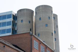 <p><span>BEKIJK OOK ONS FILMPJE! Klik hierboven op het 'scherm-icoontje'! </span></p><p><span>Wonen op een uitzonderlijke locatie met panoramisch uitzicht: exclusief appartement in de iconische Silo's!</span></p><p><span>Het Project Kanaal van Axel Vervoordt is een unieke bestemming waar wonen, kunst, architectuur en gastronomie samenkomen. Omgeven door water, groen en indrukwekkende industriële erfgoedarchitectuur geniet u hier dagelijks van rust, ruimte en een inspirerende leefomgeving. Authentieke elementen, tijdloze architectuur en duurzame materialen vormen samen een unieke leefomgeving waar karakter, comfort en esthetiek perfect in balans zijn. Dankzij de strategische ligging in Wijnegem, vlak bij Schilde en Antwerpen, combineert deze unieke locatie het beste van twee werelden: een rustige, groene woonomgeving met alle voorzieningen en uitvalswegen in de onmiddellijke nabijheid.</span></p><p><span>Gelegen op de vierde verdieping van de Silo's geniet dit exclusieve appartement van ca. 202 m² van een panoramisch uitzicht over het Albertkanaal en het prachtig aangelegde domein. Het interieur werd ontworpen door binnenhuisarchitect Marc Lauwers en combineert tijdloze elegantie met uitzonderlijk wooncomfort.</span></p><p><span>De unieke indeling bestaat uit drie cirkelvormige ruimtes met elkaar verbonden door middel van kleine glazen bruggen en een transparant vierkant volume. Bij het binnenkomen treft u een sfeervolle bibliotheekruimte, een gastentoilet en een polyvalente kamer die dienst kan doen als logeer-, hobby- of bureauruimte.</span></p><p><span>Het hart van het appartement wordt gevormd door de indrukwekkende leefruimte met open keuken en eetgedeelte. Dankzij de grote glaspartijen aan drie zijden baadt deze ruimte de hele dag in natuurlijk licht en geniet u van een voortdurend contact met de omgeving. De hoogwaardige keuken werd sober en stijlvol vormgegeven met zeer kwalitatieve materialen en toestellen.</span></p><p><span>De tweede cirkelvormige ruimte herbergt een royale zithoek met centrale gashaard, waar de gebogen architectuur zorgt voor een warme en rustgevende sfeer.</span></p><p><span>De master suite beschikt over maatwerkkasten en een luxueuze badkamer uitgerust met een dubbel lavabomeubel, ligbad, inloopdouche en afzonderlijk toilet. De westelijke oriëntatie zorgt hier voor een aangename avondzon.</span></p><p><span>Een ondergrondse autostaanplaats is bijkomend aan te kopen voor +30.000€. Verder beschikt u over 2 eigen fietsenplaatsen en gebruiksrecht van de tuin.</span></p><p><span>Bijzonderheden: high-end afwerking, EPC-label A, ventilatiesysteem D, panoramische zichten en een unieke architecturale woonbeleving.</span></p><p><span>Maandelijkse gemeenschappelijke kosten: ca. 300€</span></p><p><span>Contacteer ons voor meer informatie of een bezoek!</span></p><p><span> </span></p><p><span> </span></p>