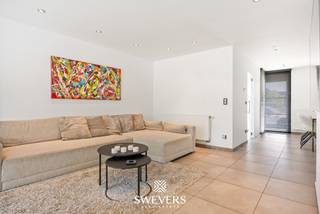 Interesse? Meer informatie op www.SWEVERS.be. - Deze instapklare gezinswoning in Hasselt biedt een praktische indeling en een uitstekende ligging op slechts 150 meter van de vernieuwde kleine ring. De woning beschikt over vier slaapkamers, een bureauruimte, een ruime leefruimte met open keuken en een aangename veranda. Dankzij de centrale locatie bevinden winkels, scholen en openbaar vervoer zich op wandelafstand, terwijl de E314 vlot bereikbaar is. De woning heeft een EPC-label A en is dus energiezuinig zonder renovatieverplichting. Op het gelijkvloers vormen de lichtrijke leefruimte, open keuken en veranda samen het hart van de woning. Grote raampartijen zorgen voor veel natuurlijk licht en een mooi zicht op de zonnige tuin. Daarnaast zijn er een ruime inkomhal, een bureauruimte, een badkamer en een aparte wasplaats aanwezig. Op de verdieping bevinden zich drie ruime slaapkamers en een compacte extra kamer die perfect kan dienen als bureau of dressing. De woning combineert comfort, functionaliteit en een topligging, waardoor ze ideaal is voor gezinnen die op zoek zijn naar een instapklare thuis in Hasselt. Bel ons vandaag nog voor een persoonlijke rondleiding. Wij van Swevers Real Estate helpen je maar al te graag verder. tel. 011 255 155. Bron bewoonbare oppervlakte: EPC-verslag.