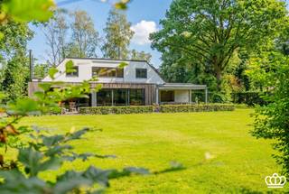 <p><span>Goed gelegen, ruime en lichte villa ideaal voor het combineren van wonen/werken of zorg wonen. <br />De villa omvat o.a. lichte leefruimtes met zicht op de tuin, 3 slaapkamers, 2 badkamers, multifunctionele ruimte met eigen ingang, berging, 2 inpandige garages en een overdekt terras op een zuid gericht perceel van 2.019 m², achteraan grenzend aan bos. </span></p><p><span> </span></p><p><span>INDELING</span></p><p><span> </span></p><p><span>Gelijkvloers:</span><span><br />Inkomhal met rechts (voorzijde van de woning) een polyvalente ruimte (35 m²) met grote raampartij op tegelvloer die kan dienen als kantoor, werkruimte of studio voor inwonende ouders / personeel met eigen terras. Aan de andere zijde van de inkomhal is een vestiaireruimte met gastentoilet en doorgang naar de leefruimtes aan de  achterzijde van de woning met grote ramen uitkijkend over de tuin, onderverdeeld in een zithoek met speksteenkachel, een eethoek en een moderne keuken met eiland en ontbijthoek, via de keuken rechtstreeks toegang tot het overdekte terras met ingemaakte kasten. Achter de keuken een bergruimte en doorgang naar de (voormalige) inpandige garage voor 1 wagen met een aanpalende wasplaats en een ruime 2</span><span><sup>e</sup></span><span> garage voor 2 wagens.</span></p><p><span> </span></p><p><span>1e verdieping: </span><span><br />Via een trap in de vestiaireruimte toegang tot de ruime en lichtrijke nachthal die kan dienen als open kantoor / speelruimte met zicht over de achtertuin en toegang biedt tot de Masterbedroom onderverdeeld in een dressing, een lager gelegen slaapkamer met kasten en badkamer met ligbad, douche en lavabo. Verder op deze verdieping nog 2 slaapkamers op parket met ingemaakte kasten en bureau, een vernieuwde douchekamer met inloopdouche en lavabo, apart toilet op de nachthal. </span></p><p><span> </span></p><p><span>Tuin:</span><span><br />De woning is omgeven door een open en lichtrijke Zuid gerichte tuin met achter de woning een ruim en deels overdekt terras en direct grenzend aan het bos. Aan de voorzijde bevindt zich nog een ruime parkeergelegenheid. </span></p><p><span> </span></p><p><span>Bijzonderheden:</span></p><p><span>-Ideale woning voor het combineren van wonen, werken of zorgwonen.</span></p><p><span>-Elektra is conform.</span></p><p><span>-Zonnepanelen aanwezig.</span></p><p><span>-CV op gas, gelijkvloers middels vloerverwarming en radiatoren op de verdieping.<br />-Screens op de ramen aan de zuidgevel.</span></p><p><span> </span></p><p><span> </span></p>