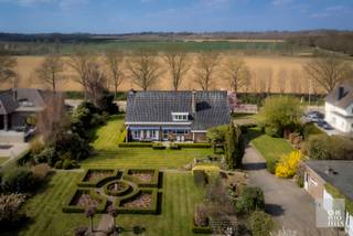 <span><strong>Indeling<br /></strong></span>
<p>Deze villa heeft een eigen, privé inkomhal. Op de begane grond bevindt zich de inkomhal met gastentoilet, een ruime woonkamer met haard, een eetkamer en een lichtvolle keuken. Dankzij de grote raampartijen geniet u hier van een prachtig uitzicht op de tuin en het terras. Aansluitend vindt u een wasplaats. Aan de zijde van de woning is er een aparte ingang die toegang biedt tot de praktijkruimte. Voor het cliënteel zijn er twee parkeerplaatsen voorzien aan de voorzijde van het huis.</p>
<p>Op de eerste verdieping leidt de nachthal naar vier slaapkamers. Daarnaast is er een recent gerenoveerde badkamer. Er bestaat de mogelijkheid om een vierde slaapkamer in te richten.</p>
<p>De tuin is zuidoostelijk georiënteerd en is voorzien van een terras. Ook is er een garagegebouw met plaats voor drie voertuigen, een autobrug en een hobbykamer.</p>
<span><strong>Afwerking<br /></strong></span>
<p>De maatkeuken is volledig uitgerust met alle benodigde apparatuur, waaronder een kookplaat met dampkap, een dubbele spoelbak, een oven, een microgolfoven, een vaatwasser en een koelkast.</p>
<p>De badkamer is voorzien van een douche, een ligbad en een dubbele wastafel geïntegreerd in het meubel.</p>