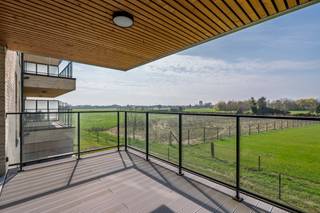 <p><strong>Wonen tussen de velden, met de stad binnen handbereik</strong></p>
<p>Sommige plekken combineren het beste van twee werelden. Het nieuwe Klokbekererf in Oud-Turnhout is zo'n plek. Deze nieuwe, doodlopende verkaveling in Oosthoven ligt op de grens van uitgestrekte velden en open landschap, terwijl het centrum van Oud-Turnhout, Turnhout en Oosthoven zich op slechts enkele minuten bevindt.</p>
<p>Hier wordt u elke dag omringd door rust, groen en ruimte. Aan de achterzijde strekt het uitzicht zich uit over de agrarische gebieden tot aan de iconische Turnova-toren in Turnhout. Aan de voorzijde kijkt u uit op een groene zone met wadi. Doorgaand verkeer is er niet, waardoor privacy, veiligheid en stilte hier vanzelfsprekend zijn. Bovendien geniet u van optimale zonoriëntaties en wordt parkeren volledig ondergronds georganiseerd.</p>
<p>Dit ruime hoekappartement in residentie "Erf" biedt een woonoppervlakte van 108,6 m² + een terras van 14,1 m². Het werd ontworpen met aandacht voor comfort, licht en leefkwaliteit. Via de inkomhal met gastentoilet en vestiaire komt u in de royale leefruimte, waar natuurlijke lichtinval langs twee zijden binnenvalt. De ruimte vormt een harmonieus geheel van zithoek, eetkamer en open leefkeuken, aangevuld met een praktische berging/wasplaats.</p>
<p>Een groot schuifraam verbindt de leefruimte met het zonnige terras. Dankzij de ideale westoriëntatie geniet u hier van lange zomeravonden met een prachtig uitzicht over de achterliggende velden.</p>
<p>Verder beschikt het appartement over 3 volwaardige slaapkamers, waarvan 1 met een eigen balkon. De badkamer krijgt aangenaam daglicht dankzij een raam en biedt plaats aan een ligbad, een inloopdouche en een dubbele wastafel.</p>
<p>De residentie is kleinschalig en omvat slechts 12 appartementen. Ondergronds heeft u de keuze uit ruime staanplaatsen of afgesloten garages, telkens met achterliggende (fietsen)berging. De lift bedient alle verdiepingen en voor bezoekers is er voldoende parkeergelegenheid binnen de verkaveling.</p>
<p>Ook op technisch vlak is dit een appartement die klaar is voor de toekomst. U koopt hier een echt BEN-appartement (Bijna Energie Neutraal), uitgerust met een individuele warmtepomp, een eigen zonnepaneleninstallatie van 2.000 Wp, vloerverwarming, ventilatie C en een doorgedreven isolatie met onder meer 11 cm vloerisolatie en 14 cm isolatie in de buitenmuren. Deze duurzame technieken zorgen voor een bijzonder laag energieverbruik en een hoog wooncomfort.</p>
<p><strong>De prijs van het appartement bedraagt 307.482 euro, exclusief aankoopkosten (btw en registratierechten) en staanplaats. Staanplaatsen met eigen berging of afgesloten garages zijn beschikbaar vanaf 27.000 euro, exclusief aankoopkosten. </strong>Voor dit volledig afgewerkte appartement, inclusief staanplaats met berging en alle aankoopkosten (btw, registratierechten, notariskosten, aktekosten en aansluitingen van de nutsvoorzieningen), bedraagt de totale investering ongeveer 404.000 euro.</p>
<p>Bent u op zoek naar een energiezuinig appartement op een unieke locatie waar rust, ruimte en bereikbaarheid samenkomen? Dan maken wij graag tijd vrij om u het project ter plaatse te laten ontdekken. In de nabijgelegen residentie "Klok" kunnen we nog enkele appartementen op andere verdiepingen aanbieden.</p>