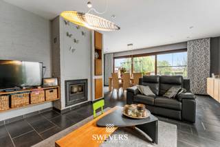 Voor meer info en foto’s, surf naar www.swevers.be – Ontdek deze uitzonderlijk ruime kangoeroewoning op een perceel van 19a 67ca in het gegeerde Kuringerheide, vlak bij Hasselt en natuurgebied De Platwijers. De woning werd gebouwd in 1980 en in 2006 functioneel omgevormd tot een volwaardige kangoeroewoning. Met een bewoonbare oppervlakte van 337 m², een gunstig EPC-label B en een praktische indeling is dit de ideale thuis voor grote gezinnen, inwonende familie of wie wonen en zorg wil combineren. De hoofdwoning beschikt over een lichtrijke leefruimte, keuken, bureau, slaapkamer en badkamer op het gelijkvloers. Op de verdieping bevinden zich meerdere slaapkamers, waardoor de woning in totaal zeven slaapkamers telt. Daarnaast zijn er drie badkamers aanwezig. De aparte woonunit beschikt over een eigen inkomhal, leefruimte met keuken, slaapkamer en badkamer, zodat privacy en zelfstandigheid verzekerd zijn. Onder de volledige woning bevindt zich een ruime kelder van 88 m², ideaal als opslag-, hobby- of werkruimte. Buiten geniet u van een dubbele carport, een zuidgerichte tuin en een heerlijk zwembad waar u in alle rust kan ontspannen. Airconditioning en rookdetectoren zorgen voor extra comfort. De woning biedt bovendien alle mogelijkheden om ze verder naar eigen smaak te moderniseren. Dankzij de rustige ligging bevinden scholen, winkels, openbaar vervoer en het centrum van Hasselt zich op korte afstand, terwijl ook de autosnelwegen vlot bereikbaar zijn. Een unieke eigendom met veel ruimte, flexibiliteit en toekomstmogelijkheden. Voor meer informatie, bel 011 255 155. Bron bewoonbare oppervlakte: EPC – verslag.