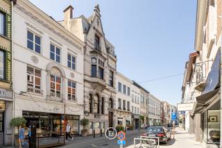 Dit charmant herenhuis, gelegen in de winkelstraat van Oudenaarde, is een unieke stadswoning met mogelijkheid om een handelspand uit te baten. De woning geniet verscheidene authentieke materialen en details.<br /><br />Een royale inkomhal voorzien van marmeren accenten, verwelkomt u en leidt naar het commerciële gedeelte op de begane grond. Hier bevindt zich een atelier en verkoopruimte beide afgewerkt met granieten elementen. Daarnaast zijn er een toilet, een bijkeuken, technische ruimte, een kluis en twee trappen die toegang bieden tot twee kelders. Het handelspand geeft uit tot een binnenkoer. Bovendien geniet deze van een zonnige tuin, een dakterras, een ruime garage en een carport, allemaal bereikbaar via de achterliggende straat, wat een onschatbare toegevoegde waarde biedt in centrum Oudenaarde.<br /><br />De prachtige inkomhal met vestiaire en gastentoilet geeft toegang tot een salon met open haard, eetplaats en keuken met berging. <br /><br />Op de tussenverdieping vinden we de wasplaats en de eerste badkamer voorzien van een dubbele lavabo, douche, bad en toilet. <br /><br />De eerste verdieping heeft 2 slaapkamer die door de grote raampartijen genieten van veel natuurlijk licht.<br /><br />De bovenste verdieping beschikt opnieuw over 2 slaapkamers en badkamer met toilet, dubbele lavabo en bad. Daarnaast is nog een vaste trap met toegang tot de zolder. Hier is nog voldoende opbergruimte. <br /><br />Dit buitengewone pand combineert niet alleen een uitstekende zichtbaarheid en bereikbaarheid , maar biedt ook een exclusieve kans om te wonen in het hart van Oudenaarde.