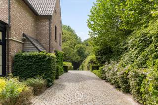 Een tijdloze villa in Genk, verscholen in het groen op een omheind perceel van 42 are. Achter de karaktervolle gevel in Vlaams kruisverband ontvouwt zich een ruime woonbeleving met warme materialen, parket, open haard en een orangerie met gashaard die het licht rijkelijk binnenbrengt.<br /><br />Met 4 slaapkamers, 2 badkamers en een afzonderlijk praktijkgedeelte met eigen inkom leent de woning zich zowel voor wonen als werken. De discrete ligging, verwarmde privé-oprit en vlotte verbinding naar het ZOL en de E314 brengen rust, privacy en bereikbaarheid samen.