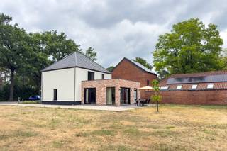 Ruim wonen, vlot bereikbaar zijn én binnen enkele minuten tussen de bossen staan? Aan de Kiezelweg in Mol hoef je gelukkig niet te kiezen.<br /><br />Deze vrijstaande woning werd in 2021 van A tot Z gerenoveerd door een aannemer en kreeg een frisse, strak-klassieke uitstraling. Vooraan zorgen de wit geschilderde gevel, zwarte ramen en aangelegde voortuin voor een verzorgde eerste indruk. Parkeren kan op de twee aangelegde plaatsen én op de ruime oprit, waar minstens zes wagens terechtkunnen.<br /><br />Binnen kom je via de ruime inkomhal, waar de technieken netjes achter kastdeuren verdwenen zijn. Verder vind je hier een gastentoilet en toegang tot de open leefruimte.<br /><br />En die leefruimte is meteen het hart van de woning. Wonen, eten en koken vloeien hier mooi in elkaar over, met zachte tinten, warme houtaccenten en grote raampartijen op een zuidgerichte tuin.<br /><br />De keuken is volledig uitgerust met een inductiekookplaat, spoelbak, koelkast, vaatwasser, oven en microgolfoven. Het ruime kookeiland biedt vier zitplaatsen.<br /><br />Aansluitend ligt de praktische berging en wasruimte met een aparte achterinkom. Op het gelijkvloers bevindt zich ook een ruime badkamer met ligbad, douche en twee lavabo’s.<br />De eerste verdieping telt een grote master bedroom met ingerichte maatwerkdressing, een ruime kinderkamer, een tweede badkamer met douche en dubbele wastafel, en een apart toilet. Nog een verdieping hoger bereik je via de vaste trap een volledig afgewerkte, open zolderruimte.<br /><br />Buiten beschik je over een perceel van in totaal maar liefst 31,5 are. De voortuin en parkeerzones zijn al aangelegd; de grote achtertuin kan nog volledig naar eigen smaak worden ingericht.<br /><br />Ook technisch staat de woning sterk, met vloerverwarming op gas op het gelijkvloers, dubbele beglazing, een alarmsysteem met raam- en deursensoren en een laadpaal. Met een EPC-score van 111 kWh/m² behaalt de woning bovendien een mooi B-label.<br /><br />