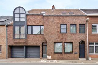 Voor meer info en foto’s, surf naar www.swevers.be – Op een strategische locatie in Tessenderlo-Ham ontdek je deze uitzonderlijk ruime rijwoning met een bewoonbare oppervlakte van 365 m² op een perceel van 8a 75ca. De woning werd oorspronkelijk gebouwd in 1948 maar onderging meerdere renovaties: een nieuw dak (1989), vernieuwde ramen (2015) en een moderne keuken (2018). De gelijkvloerse verdieping biedt o.a. een leefruimte van 50 m², aparte eetkamer, ruime keuken (28,6 m²), badkamer, wasplaats en een garage van 40 m². Daarnaast zijn er praktijkruimtes met aparte ingang, ideaal voor zelfstandigen. Op de eerste verdieping vind je drie grote slaapkamers, een tweede badkamer, apart toilet en een extra kamer die als dressing of bureau kan dienen. De zolderverdieping is volledig ingericht als extra woongedeelte met woonkamer, aansluitingen voor een keuken, slaapkamer of polyvalente ruimte van 55 m², vijfde slaapkamer, zesde slaapkamer of polyvalente ruimte en balkon. Dankzij de zonnepanelen en zonneboiler, gunstige oriëntatie en centrale ligging nabij winkels, scholen en openbaar vervoer, is dit een ideale woning voor grote gezinnen of wie wonen en werken wil combineren. Voor meer informatie, bel 011 255 155. Bron bewoonbare oppervlakte: EPC – verslag.
