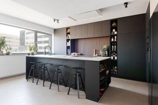 Gelegen op de vierde verdieping en bereikbaar via de lift, betreedt men dit appartement via een verzorgde inkomhal. Deze geeft uit op een ruime leef- en eetruimte met eiken parket. Dankzij de brede gevel en de grote raampartijen geniet de ruimte van veel natuurlijke lichtinval.

Aansluitend bevindt zich de open keuken, visueel gescheiden van de leefruimte door een wand. Zowel de keuken als de inkomhal zijn afgewerkt met een nieuwe beton ciré-vloer. De keuken werd volledig vernieuwd en beschikt over een groot keukeneiland met veel werk- en opbergruimte. De keuken is uitgerust met kwalitatieve toestellen, waaronder een AEG-inductiekookplaat, vaatwasser, combi-oven tot 250°C met zelfreiniging, een Amerikaanse koelkast en een Quooker-kraan. Het werkblad is uitgevoerd in keramiek met travertinlook. Op deze verdieping bevinden zich verder nog een apart gastentoilet en een praktische berging.

Via de trap bereikt men de bovenverdieping. Deze geeft uit op een ruim, zuidwestgericht zonneterras met zicht op het MAS. Op deze verdieping bevinden zich twee slaapkamers, waaronder een ruime masterbedroom met aansluitende dressing, voorzien van maatkasten. Beide slaapkamers zijn uitgerust met airconditioning.

De vernieuwde badkamer beschikt over een inloopdouche, een vrijstaand bad en waskommen in solid surface-materiaal.

Tot slot is er de mogelijkheid om een ondergrondse autostaanplaats aan te kopen, niet inbegrepen in de vraagprijs.