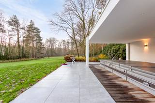 <p>Voor deze knappe eigendom klinken superlatieven te bescheiden. Het is werkelijk indrukwekkend, fenomenaal, magnifiek! Voor wie houdt van discretie, rust, luxe en privacy.</p>
<p>Na een 70m lange oprijlaan verschijnt een elegante gevel die je onmiddellijk doet dromen: je waant je in de Hamptons, New York. De recent vernieuwde gevelbekleding doet de woning schitteren in haar nieuwe jasje. Een lang bordes nodigt je uit om de woning te ontdekken.</p>
<p>Binnen kijk je je ogen uit in de royale inkomhal met keizerlijke trap, die naar de bibliotheek en slaapvertrekken leidt.</p>
<p>GELIJKVLOERS:</p>
<p>In de rechtervleugel bevinden zich de dubbele garage met berging, vestiaire, en de logeerkamer met en suite gastenbadkamer.</p>
<p>In de linkervleugel ligt de bureauruimte waar het rustig werken is, en die ruim genoeg is om klanten op aangename wijze te ontvangen; en een gastentoilet.</p>
<p>Aan de achterzijde bevindt zich de gigantische leefruimte met keuken: het kloppende hart van de woning, met een adembenemend zicht op de tuin.</p>
<p>Dit deel is bijzonder stijlvol vernieuwd, met een hedendaagse look &amp; feel en hoogwaardige materialen. Een grote gashaard, gezellige zitput, gimmicks zoals een verdwijnend raam en doorkijk naar de keuken, maken dat deze ruimte op verschillende momenten van de dag anders aanvoelt. Het grote panoramische raam is als een landschapsschilderij, maar dan van de eigen tuin. De keuken is volledig geëquipeerd en wordt geflankeerd door een enorm overdekt terras, waardoor het binnen-buitengevoel compleet is. Dit is een woning waar je ultiem kan genieten, en je graag veel tijd in wil doorbrengen.</p>
<p>VERDIEPING:</p>
<p>Linkervleugel: hier bevindt zich de grootste badkamer, een behoorlijk futuristisch ontwerp met centraal element waarrond de verschillende functies zich bevinden: ruime douche, hoekbad, dubbele lavabo, omkleedhoek. Aansluitend bevindt zich een praktische wasplaats, strijkruimte en apart toilet.</p>
<p>Een dressing leidt naar de comfortabel ruime master bedroom met zicht op de tuin, die naar een tweede open dressing of extra slaapkamer leidt. Ernaast bevindt zich een fitnessruimte die een derde slaapkamer kan zijn.</p>
<p>In de rechtervleugel bevinden zich 2 prachtige ruime slaapkamers met mezzanine - een droom voor vele tieners – en een derde badkamer met ligbad en douche completeert het geheel.</p>
<p>Samen komen we op 6 slaapkamers in het totaal, 5 boven en 1 beneden, plus een dressing boven en bureau beneden. Ideaal voor wie ruim wil wonen, samengesteld gezin, werken &amp; wonen, B&amp;B en wonen, etc.</p>
<p>KELDER</p>
<p>Uiterst praktisch is de enorme kelder die deels verwarmd is, met hobbyruimtes, wijnkelder en opslagruimtes. Verder is er nog een kruipkelder.</p>
<p>TUIN:</p>
<p>In de tuin aansluitend aan de oprit, bevindt zich een knap bijgebouw met aparte fietsenberging, berging voor alle tuinonderhoudsmaterialen, en ruimte voor sport en ultieme ontspanning: een zwemspa met jetstream &amp; onderwaterloopband, en een heerlijke jacuzzi. Wellness in eigen tuin.</p>
<p>De tuin zelf is een prachtig glooiend gazon met zuid-zuidwest oriëntatie, omzoomd met struiken, bloemen en grote bomen. Mooi aangelegd èn beperkt in onderhoud zodat je er ook echt van kan genieten.</p>
<p>Halverwege de tuin loopt het hoofdperceel over in 2 percelen bouwgrond (85B en 85C op het bijgevoegde plan), die mee aangekocht kunnen worden aan respectievelijk 300.000eur en 325.000eur, maar die niet allebei absoluut noodzakelijk zijn om het weidse aspect te behouden.</p>
<p>Technisch is deze woning uitgerust met warmtepompen, airco, dak- en muurisolatie, hoogrendementsglas, alarm en camera’s, domotica, een conforme state-of-the-art elektrische installatie, en mèt een EPC A, wat zeer uitzonderlijk is voor dit type woning en uiteraard een enorme troef!</p>
<p>Geïnspireerd en klaar om deze droomwoning te ontdekken? Maak dan graag een afspraak met Tinne op 0477 60 21 99 of tinne.schotsmans@quares.be</p>