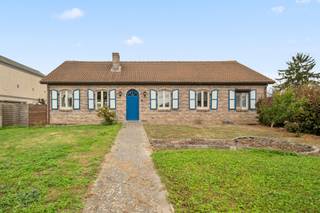 <p><span>Découvrez cette charmante maison de plain-pied située dans le paisible village de Hoeleden (Kortenaken), sur un magnifique terrain de pas moins de 2 266 m². Avec sa façade pleine de caractère, ses volets bleus et son vaste jardin, cette propriété offre de nombreuses possibilités à ceux qui recherchent calme, espace et intimité.</span></p>
<p><span>Dès l’entrée, le hall vous accueille et vous mène vers la spacieuse pièce de vie, où le poêle à bois crée une atmosphère chaleureuse et conviviale. La cuisine ouverte entièrement équipée s’intègre harmonieusement à l’espace de vie. La véranda constitue un agréable espace supplémentaire pour se détendre tout en profitant d’une belle vue sur le jardin.</span></p>
<p><span>La maison dispose également d’une salle de bains avec baignoire, douche et double lavabo, d’une grande chambre ainsi que d’une seconde pièce particulièrement spacieuse, actuellement aménagée en bureau. Cette pièce peut facilement être à nouveau divisée, permettant ainsi de créer trois chambres.</span></p>
<p><span>L’un des atouts majeurs de cette propriété est son très grand sous-sol, offrant pas moins de 123 m² d’espace supplémentaire, idéal pour le rangement, les loisirs ou l’aménagement d’un espace de travail. La maison dispose également d’un garage intégré et de possibilités de stationnement sur la propriété.</span></p>
<p><span>Le vaste jardin constitue sans aucun doute un autre atout majeur de cette propriété. Avec une parcelle de 22 ares, vous disposez de beaucoup d’espace pour profiter pleinement de la vie en plein air, aménager un potager ou accueillir des animaux.</span></p>
<p><span>Vous êtes à la recherche d’une maison située au calme, avec beaucoup d’espace extérieur et de nombreuses possibilités ? Alors cette charmante propriété à Hoeleden mérite certainement une visite !</span></p>
<p><span>Vous souhaitez organiser une visite ? Contactez-nous au 016 23 21 45.</span></p>