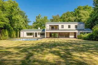 In de rustige en groene Kasteeldreef te Schilde vindt u deze ruime vrijstaande villa op een mooi perceel met zwembad, dubbele garage en veel potentieel. De woning is degelijk gebouwd en biedt een functionele indeling met volop ruimte voor een gezin, hobby of thuiswerk.<br />Op het gelijkvloers komt u binnen via een inkomhal met marmeren vloer. De leefruimte is ingedeeld in verschillende zones: een zithoek met haardvuur en zicht op de tuin, een verhoogde bar en een tweede leefhoek. Vanuit deze ruimtes is er directe toegang tot de tuin. De keuken kijkt uit op het groen en heeft eveneens een deur naar buiten.<br />Verder zijn er op het gelijkvloers een was- en droogberging met extra opbergruimte, een aparte zithoek met tuintoegang, een toilet met lavabo, en toegang tot de kelder. De kelderverdieping beschikt over meerdere droge kelders, een extra kast, wateraansluiting en de gasmeter.<br />Op de eerste verdieping bevinden zich drie ruime slaapkamers, een badkamer met dubbele lavabo en bad, en een apart toilet. De grote master bedroom heeft een ensuite badkamer (ligbad, dubbele lavabo), een aparte dressing en een terras. Op deze verdieping vindt u ook een vierde slaapkamer met een klein lavabootje, een sauna, douche en een tweede apart toilet.<br />De tuin is volledig omsloten en beschikt over een groot zwembad. Er is een ruime oprit met automatische poort en een inpandige garage voor twee wagens. Aan de zijkant van het huis is een aparte toegang tot bergruimte voor zwembadmateriaal. Daarnaast grenst er aan het huis een poolhouse met een vestiaire, opbergruimte, grote ontspanningsruimte, douche, toilet, lavabo en omkleedruimte.<br />Deze woning is solide, biedt veel mogelijkheden, maar vraagt hier en daar wat opfrissingswerken.