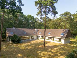 Op een prachtig, bosrijk perceel nabij het centrum van Kapellen bevindt zich deze bijzonder ruime villa uit de jaren '70. Dankzij haar royale volumes, doordachte indeling en unieke ligging vormt deze eigendom de ideale basis voor wie op zoek is naar een renovatieproject met enorm potentieel.<br /><br />Via de ruime inkomhal met gastentoilet en vestiairekasten betreedt u de lichtrijke leefruimte, bestaande uit een gezellige zithoek, een sfeervolle lager gelegen zitput met open haard en een open eetkamer. Grote raampartijen zorgen voor een mooie verbinding met de tuin en alle leefruimtes kunnen afzonderlijk worden afgesloten met een schuifwand. Aansluitend bevindt zich een praktisch kantoor met ingemaakte kasten.<br /><br />De ingerichte leefkeuken werd reeds vernieuwd en is voorzien van de nodige toestellen. Verder beschikt de woning over een dubbele inpandige garage met aansluitingen voor wasmachine en droogkast en een extra bergruimte.<br /><br />Op het gelijkvloers bevinden zich maar liefst vier slaapkamers en vier badkamers, wat tal van mogelijkheden biedt voor grote gezinnen, een kangoeroewoning of een combinatie van wonen en werken.<br /><br />De later toegevoegde verdieping, bereikbaar via een vaste trap, is nog volledig naar eigen smaak af te werken en biedt extra uitbreidingsmogelijkheden.<br /><br />Hoewel de woning een grondige renovatie vereist, biedt ze dankzij haar uitstekende locatie, ruime bewoonbare oppervlakte en uitzonderlijke indeling een unieke kans om een exclusieve droomwoning te creëren.<br /><br />De woning is rustig gelegen in een groene, residentiële omgeving, op korte afstand van het centrum van Kapellen. Winkels, scholen, openbaar vervoer en sportfaciliteiten bevinden zich in de nabije omgeving. Dankzij de vlotte verbinding naar Antwerpen en Nederland geniet u hier van een ideale combinatie van rustig wonen en een uitstekende bereikbaarheid.