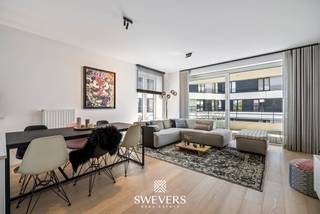 Voor meer info en foto’s, surf naar www.swevers.be – Dit recent appartement op de tweede verdieping van een verzorgde residentie (bouwjaar 2017) aan de Scheepvaartlaan in Hasselt combineert comfort met een moderne afwerking. Met een bewoonbare oppervlakte van 91 m² geniet je van een doordachte indeling en veel natuurlijk licht. De leefruimte van 23 m² vormt het hart van het appartement en sluit naadloos aan op het ruime terras van 28 m² met zicht op het kanaal. De open keuken (9,95 m²) is uitgerust met kwalitatieve toestellen van Miele en Bora en beschikt over een onderhoudsvriendelijk keramisch werkblad. Via de inkomhal bereik je het aparte toilet, een praktische berging met aansluitingen voor wasmachine en droogkast, en de centraal gelegen badkamer met inloopdouche en lavabo. De slaapkamer van 16 m² ligt rustig achteraan en geeft toegang tot een tweede terras van 4 m². Volgens het plan kan eenvoudig een tweede slaapkamer worden ingericht. Extra troeven zijn de kelderberging, ondergrondse fietsenstalling, gemeenschappelijke tuin en laadmogelijkheid voor elektrische wagens. De ligging is ideaal: op wandelafstand van winkels en horeca, nabij Quartier Bleu en het centrum, met vlotte verbindingen naar scholen, openbaar vervoer en snelwegen. Een autostaanplaats is apart aan te kopen voor €35.000. Voor meer informatie, bel 011 255 155. Bron bewoonbare oppervlakte: EPC – verslag.