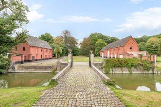 At the border of East and West Flanders, where Kruisem, Nokere and Waregem meet, lies an estate that has enjoyed this location for centuries. The estate is accessible via a cobbled driveway with an iron entrance gate. The preserved moat and the old trees surrounding it provide a unique setting and privacy.<br /><br />The castle dates back to the eighteenth century and is built in the Louis XVI style, with a symmetrical facade and refined detailing that has stood the test of time. The park, with its entrance bridge and courtyard, completes the whole and testifies to a thoughtful layout.<br /><br />The entrance hall with Ionic pilasters and a marble floor forms a representative entrance to the castle. The adjacent living spaces have been carefully maintained over time and have retained their original character.<br /><br />In addition to the castle, the estate includes two outbuildings, formerly used as a coach house and caretaker's residence, and a garden pavilion from the nineteenth century. These buildings offer possibilities for a complementary use alongside the residential function, such as an office space for a family office, a home practice, small-scale tourist accommodation, or a granny flat. Such ancillary function needs to be discussed with the urban planning department.<br /><br />The estate covers 4.4 hectares, providing the space and privacy befitting a property of this level. Kasteel Herlegem is an authentic and representative estate for those seeking character in the vicinity of Waregem, Ghent, Kortrijk and Oudenaarde.