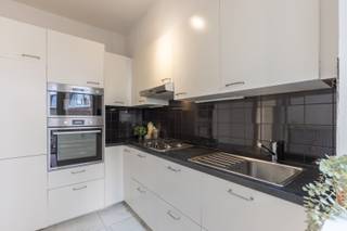 Welkom in dit appartement op het 1ste verdiep van een goed onderhouden gebouw! Via een stevige veiligheidsdeur kom je in een ruime, open hal terecht. Van hieruit betreed je een grote leefruimte met kamershoge ramen langswaar het zonlicht overvloedig binnenstroomt. De ramen zelf zijn slechts enkele jaren geleden geplaatst. De keuken en badkamer zijn recent gerenoveerd en de elektrische installatie is hierbij conform gemaakt. De twee slaapkamers liggen aan de achterkant waar het rustig vertoeven is.<br /><br />In de buurt van de woning liggen er tal van restaurantjes, bakkerijen, slagers en andere zaken uit alle hoeken van de wereld. Het Centraal Station ligt slechts op enkele minuten wandelafstand. En dankzij haar centrale ligging ben je zo in het historisch centrum waar je lekker kunt shoppen of culturele hotspots kunt bezoeken.<br /><br />Wordt dit je toekomstig stulpje? Kom het snel ontdekken!<br /><br /><br /><strong>Indeling</strong><br />Hal (4,8 m²).<br />Leefruimte (37,2 m²).<br />Keuken (7,5 m²).<br />Toilet.<br />Douchekamer (4,2 m²).<br />Slaapkamer 1 (10,2 m²).<br />Slaapkamer 2 (16,0 m²).<br />Terras (3,2 m²)<br /><br />Kelderberging (6 m²).<br /><br /><strong>Extra</strong><br />Gemeenschappelijke kosten: 230 euro/maand (syndicus, blokpolis, onderhoud liften, enz.) + 140 euro/maand (verwarming en water).<br />Aparte meter voor elektriciteit.  <br />Elektrische installatie: AREI-conform.<br />EPC: B.<br /><br />(woongebied, vergunning, geen verkavelingsvergunning, voorkooprecht, geen rechterlijke herstelmaatregel)