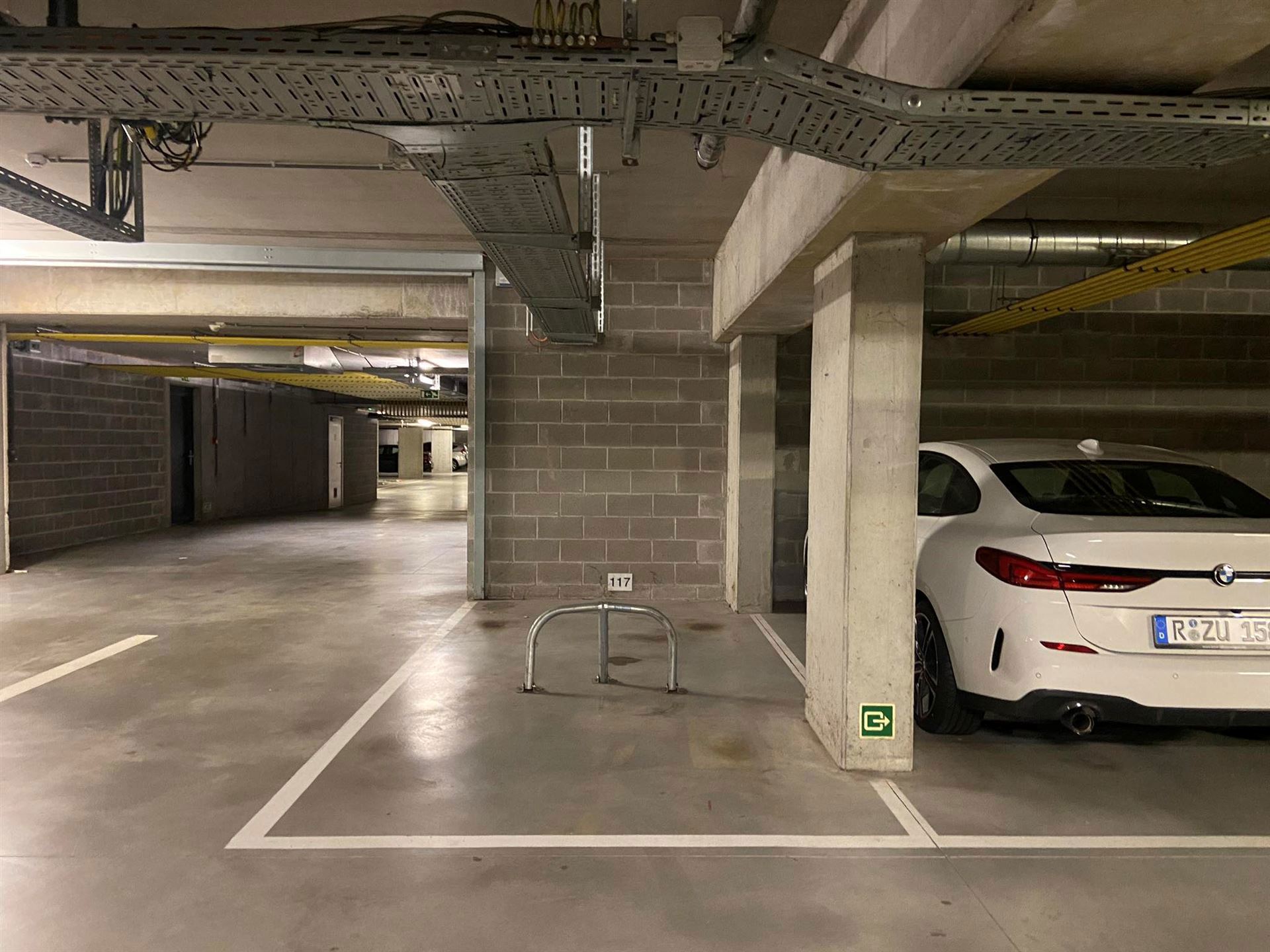 Staanplaats P117 met parkeerbeugel in de kelderverdieping van residentie Leiemeersen II.