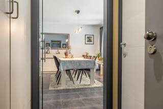 Centraal gelegen op het Begijnhofplein in Halen vinden we dit gelijkvloers appartement. Residentie ‘De Rivieren’ werd gebouwd in 2012 en bestaat in totaal uit 28 appartementen. Nummer 1, waar het appartement gelegen is, telt 7 app. De gelijkvloerse verdieping telt 2 app.

We komen binnen in de inkomhal, met een apart toilet, en ruimte voor een vestiairekast. Via de glazen deur komen we in de ruime woonkamer (34 m²), van waaruit we toegang hebben tot het terras vooraan (8 m²). Naastliggend vinden we de open keuken (8 m²), die voorzien is van kookplaat, afwasmachine, oven, koelkast en wasbak. In de berging (5 m²) vinden we de aansluiting voor het wasmachine.

Het appartement telt twee grote slaapkamers (13 en 11 m²). Via de slaapkamers hebben we toegang tot het zeer ruime terras (42 m²) aan de achterzijde. De badkamer (9 m²) is uitgerust met ligbad, douche en badkamermeubel met lavabo. 

Bij het appartement hoort tevens een ondergrondse autostaanplaats en een handige kelderberging (5 m²), die te bereiken is via de lift of de trap. Ook vinden we hier een gemeenschappelijke fietsenberging. De kelderverdieping is uitgerust met camerabewaking.

Het appartement wordt verwarmd op aardgas en heeft ramen met dubbel glas (aluminium-profielen). De ramen van de slaapkamers zijn uitgerust met rolluiken. Hierdoor heeft het appartement een gunstig EPC met label B (110 kWh/m² jaar). De elektriciteit is conform het AREI. 

Er is een syndicus en de vaste kosten bedragen 91 euro per maand. 