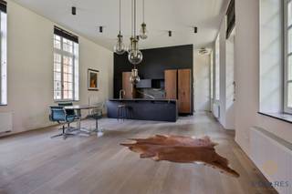 In de bossen van Lovenjoel vinden we dit fantastisch gelijkvloers appartement met twee slaapkamers en enorm veel cachet.<br /><br />Niet alleen omdat het gelegen is in een uniek project, omgeven door natuur en met een rijke erfgoedwaarde, maar ook omdat het interieur zo knap ontworpen werd, dat het in een interieurmagazine werd aanbevolen.<br /><br />Bij het binnenkomen in het appartement, vallen onmiddellijk de warme materialen, hoge plafonds en rijkelijke lichtinval op. Het creëert een enorme sfeer die niet makkelijk vergeleken kan worden met wat er vandaag op de markt wordt aangeboden. Het appartement betreft van oorsprong een 3 slaapkamer-indeling, waar het grondplan opnieuw werd ingetekend om twee grotere slaapkamers te creëren. Hiervan wordt vandaag een slaapkamer gebruikt als bureau.<br /><br />De ruime leefruimte met toegang naar het terras en de tuin, geeft tevens verbinding met de open keuken, een ruime technische berging, de hal, de WC en de ingemaakte vestiaire. Aansluitend aan de leefruimte vinden we dan de bureau/slaapkamer en een korte gang naar de zeer ruime master bedroom en een en-suite badkamer met ligbad, inloopdouche en WC. Deze werd tevens knap versierd met een muurschildering.<br /><br />Het appartement wordt verwarmd met gas & beschikt over een private parkeerplaats en een kelderberging. Er is ook een gemeenschappelijke fietsberging. Omgeven door natuur en zelfs een wellness, heeft dit alles te bieden om tot rust te komen.<br /><br />Contacteer ons voor een bezoek ter plaatse.