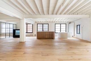 <p><strong><span>Achter deze discrete gevel schuilt één van de meest unieke loftwoningen van Mortsel.</span></strong></p>
<p><span>Sommige eigendommen zijn meer dan een woning. Ze vertellen een verhaal. Deze voormalige potloodfabriek werd in 2025 met uitzonderlijk veel respect voor haar industriële verleden volledig gerenoveerd tot een exclusieve loft van maar liefst </span><strong><span>430 m²</span></strong><span>, waar authentieke charme, hoogwaardige afwerking en hedendaags comfort perfect samensmelten.</span></p>
<p><span>Via de private inrit bereikt u de binnenkoer, waar meerdere wagens op eigen terrein kunnen parkeren. Het gelijkvloers biedt een waaier aan mogelijkheden en is volledig polyvalent ingericht. De verschillende ruime vertrekken kunnen dienst doen als exclusieve garage voor oldtimers of sportwagens, atelier, showroom, praktijkruimte, kantoor of opslag. Dankzij de aparte douche en het afzonderlijke toilet is deze verdieping ook perfect geschikt voor een vrij beroep of een combinatie van wonen en werken. Vanuit het gelijkvloers heeft u bovendien rechtstreeks toegang tot de zonnige, volledig privatieve tuin, waar rust en privacy centraal staan.</span></p>
<p><span>Met de trap of de personen- en goederenlift bereikt u de indrukwekkende loft op de eerste verdieping. Hier zorgen de hoge plafonds, grote raampartijen en overvloedige lichtinval voor een uitzonderlijk gevoel van ruimte. De originele industriële elementen werden zorgvuldig behouden en gecombineerd met warme parketvloeren en kwalitatieve materialen, waardoor een stijlvolle en tijdloze woonomgeving ontstond.</span></p>
<p><span>Centraal in de leefruimte bevindt zich de exclusieve open maatwerkkeuken, uitgevoerd in warm hout met elegante afgeronde lijnen en afgewerkt met een luxueus marmeren werkblad. Hoogwaardige inbouwtoestellen, slimme opbergruimte en een doordachte indeling maken deze keuken tot het kloppende hart van de woning.</span></p>
<p><span>De loft beschikt momenteel over een royale master suite met een vrijstaand ligbad als echte blikvanger. Daarnaast is er een tweede stijlvolle badkamer met inloopdouche en toilet. Dankzij de royale oppervlakte kunnen, indien gewenst, eenvoudig meerdere extra slaapkamers worden gecreëerd zonder afbreuk te doen aan het unieke loftgevoel.</span></p>
<p><span>Deze eigendom combineert een karaktervolle industriële architectuur met hedendaags wooncomfort. Airconditioning, een personen- en goederenlift, hoogwaardige afwerkingen, parkeermogelijkheden en een gunstig EPC-label B maken het geheel compleet.<br /><br />Belangrijkste troeven:<br />-Voormalige potloodfabriek volledig gerenoveerd in 2025<br />-Circa 430 m² bruikbare oppervlakte<br />-Exclusieve loftwoning met authentieke industriële architectuur<br />-Hoogwaardige afwerking en kwaliteitsmaterialen<br />-Personen- en goederenlift<br />-Airconditioning<br />-Polyvalente gelijkvloerse verdieping voor vrij beroep, atelier, showroom, garage of praktijk<br />-Exclusieve maatwerkkeuken met marmeren werkblad<br />-Mogelijkheid tot meerdere slaapkamers<br />-Twee stijlvolle badkamers<br />-Zonnige, volledig privatieve tuin<br />-Meerdere parkeerplaatsen op eigen terrein<br />-EPC-label B<br /></span></p>
<p><span>Een uitzonderlijke eigendom voor wie op zoek is naar ruimte, karakter en flexibiliteit. Of u nu droomt van een exclusieve loftwoning, een inspirerende werkplek of een combinatie van beide, deze unieke voormalige potloodfabriek biedt een woonbeleving die zelden op de markt verschijnt.</span></p>