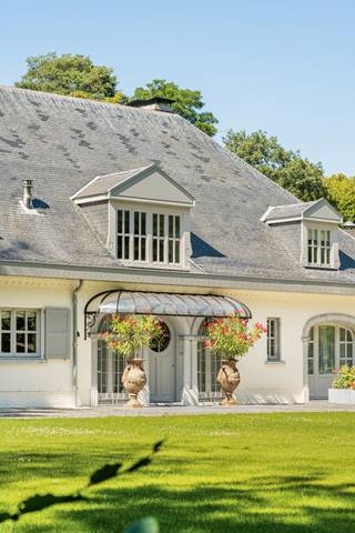 Exclusive Top Notch Villa Vriesdonk | Brasschaat<br /><br />Located in the heart of the residential villa district Vriesdonk, this exceptional, fully renovated villa (from 2024 to 2026) is realized under the direction of interior architect Rebecca Verstraeten. Surrounded by mature greenery and absolute tranquility, this property combines timeless architecture with contemporary living comfort at the highest level.<br /><br />The classic appearance - white facades, slate mansard roof, and elegant proportions - is harmoniously complemented by high-quality techniques and a refined finish. The house was designed with special attention to comfort, health, and quality of life. The villa features an integrated air conditioning system, balanced ventilation for a continuous supply of purified and healthy indoor air, as well as a central vacuum system with an external motor, which not only offers efficiency and ease of use but also contributes to an exceptionally quiet living experience.<br /><br />Reception & living spaces<br />The impressive entrance hall with marble floor and floating wrought iron staircase sets the tone immediately. High ceilings, ring windows, and wide oak plank floors create an open and light-filled atmosphere. Large windows and classic fireplaces provide a seamless connection between the living spaces and the surrounding park garden.<br />The generous open-space living area forms the heart of the house, with a ceiling height of approximately 4.20 meters, a glass skylight, a cozy wood stove, and triple French doors to the terrace and garden.<br /><br />Kitchen & dining room<br />The luxurious custom-made kitchen in sage green with marble countertops is fully equipped with a Lacanche stove, Miele appliances, wine cellar, and double dishwashers. The central dining room with an open bar directly connects to the terrace and offers an ideal setting for both daily comfort and stylish entertaining.<br /><br />Master suite & office<br />The master suite includes a spacious bedroom with integrated air conditioning and direct access to the terrace, an exclusive dressing room, and a natural stone bathroom with double sinks and walk-in shower.<br />In addition, the villa has a spacious office of approximately 36 m² with custom-made cabinets and French doors to the front garden - ideal as a private workspace or reception area.<br /><br />Wellness, fitness & indoor swimming pool<br />An absolute asset is located on the basement level: a fully developed private wellness and health area, designed to prioritize relaxation, vitality, and well-being.<br />This exclusive wing includes a heated mosaic swimming pool (approx. 6 x 11 m) with an automatic cover, sauna, jacuzzi, Turkish steam bath, high-quality in-house fitness with glass walls, a stylish massage room, and a versatile yoga, pilates, or relaxation room.<br />Through the open sliding glass dome and additional natural stone staircase, a unique connection is created between indoor and outdoor, seamlessly blending wellness and nature. In combination with the green, residential, and particularly quiet surroundings, this villa offers an exceptional living experience where health, tranquility, and comfort are central.<br /><br />An authentic brick wine cellar with reclaimed tiles from a former monastery completes this level.<br />Floors<br /><br />First floor - five full bedrooms with walk-in closets and four bathrooms finished in natural stone.<br /><br />Second floor - fully independent guest accommodation, caretaker's residence, or au pair floor with two bedrooms, open kitchen, and private bathroom.<br /><br />Garden & techniques<br />The landscaped park garden surrounding the villa ensures complete privacy and includes various sun terraces, a garden pavilion, enclosed courtyard, and generous lawns.<br />The house is equipped with advanced techniques including solar panels, renewed heating system, integrated air conditioning, home automation, balanced ventilation, central vacuum system with an external motor, and multiple charging points for electric vehicles, both under the carport and in the covered parking area at the front. There is also a water source (80m deep - drinking water quality), automatic garden irrigation, and a professional irrigation system in the garden fed via the groundwater borehole, ensuring maximum savings and ease of use.<br /><br />Location<br />Located in one of the most sought-after residential areas of Brasschaat, a short distance from renowned schools, the international school, golf, hockey and football facilities, and the main connecting roads to Antwerp and the Netherlands.<br /><br />An exceptional property where architecture, well-being, technology, and discretion come together in a luxurious living experience of international level.