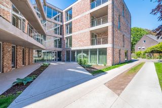 De assistentiewoning krijgt in Villa Moeie een geheel nieuwe dimensie. Grote glaspartijen vloeien moeiteloos over in een strak gebouw. Ruime, overdekte terrassen maken het mogelijk om optimaal van het buitenleven te genieten. Dit gevoel wordt versterkt door de gezamenlijke tuin, waar men onder het tuinpaviljoen kan samenkomen voor een drankje of een babbel. De groene vingers zijn in de nabijgelegen moestuin in hun sas. Sportievelingen vinden zeker hun gading aan de petanquebaan.
Dit nieuwbouwproject omvat 2 gebouwen, het villagebouw en het residentiegebouw. Beiden beschikken over een eigen technische ruimte en fietsenstalling. Hier kunnen ook scootmobiels gestald en opgeladen worden.
In het residentiegebouw op de hoek van de Moeie en de Tieltsesteenweg, worden 27 assistentiewoningen afgewisseld met gemeenschappelijke ruimtes. Hier is onder meer het bureau van de woonassistent gevestigd. Daarnaast is er ook een ontmoetingsruimte met bar en salon, bezoekerstoilet en afvalberging.
Het aparte villagebouw bestaat uit 8 assistentiewoningen, en evenveel private kelders.
De 34 parkeerplaatsen zijn als volgt verdeeld:
- 3 parkeerplaatsen voor zorgverstrekkers en woonassistenten
- 2 (minder)valide bezoekersparkeerplaatsen
- 29 privatieve parkeerplaatsen met gepersonaliseerde beveiligde toegang.
Elke flat heeft een eigen water- en elektriciteitsteller, inbraakwerende voordeur en warmtepomp. Een afzonderlijke inkomhal zorgt voor privacy, de open keuken in de lichtrijke leefruimte maakt het aangenaam om familie en vrienden te ontvangen. De slaapkamers zijn royaal van grootte, zodat een dubbel bed én een kast er makkelijk passen. In de badkamer zijn discreet hulpmiddelen aangebracht, zoals een zitje in de douche en een handgreep naast het toilet.
Het gehele park is rolstoeltoegankelijk. Doorheen het appartement kan de bewoner een alarm activeren, of de zorgassistent bereiken voor meer hulp. Kortom, sfeer, comfort en hulp waren nog nooit zo toegankelijk!
Wenst u meer info over dit unieke project?
Bel dan Nic van Unicum voor een verhelderend gesprek op 09 336 16 15.