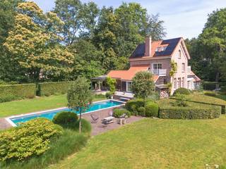 <p>In een van de meest gegeerde residentiële buurten van Brasschaat, midden in het groene Ter Borcht, bevindt zich deze karaktervolle villa op een prachtig aangelegd perceel van ca. <strong>4.850 m²</strong>. Omringd door volwassen bomen en een uitzonderlijk mooie tuin geniet u hier van absolute rust en privacy.</p>
<p>De woning, oorspronkelijk gebouwd in 1928, werd ongeveer achtien jaar geleden grondig gerenoveerd en sindsdien steeds met veel zorg onderhouden en verder gemoderniseerd. Zo werden recent nog een volledig nieuw dak, zonnepanelen en een laadpaal geplaatst.</p>
<p>Via de inkomhal met gastentoilet bereikt u het bureau, de garage en de leefruimtes. De royale woonkamer met parketvloer, open haard en gezellige zithoek baadt in het licht dankzij de grote raampartijen en biedt een prachtig uitzicht over de tuin en het zwembad.</p>
<p>De ruime leefkeuken, afgewerkt met natuursteen en voorzien van alle hedendaagse toestellen, vormt het hart van de woning en geeft rechtstreeks uit op het zonnige terras.</p>
<p>Op de eerste verdieping bevinden zich twee ruime slaapkamers, elk met een eigen badkamer. De tweede verdieping biedt nog twee bijkomende slaapkamers en een douchekamer, ideaal voor een groot gezin of gasten.</p>
<p>Buiten vormt de schitterend aangelegde tuin een ware oase van rust. Het verwarmde zwembad (14 x 4 m) met warmtepomp, de verschillende terrassen en de volwassen beplanting zorgen voor een uitzonderlijke woonbeleving in een groene omgeving.</p>