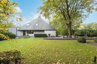 <strong>Unieke, open architectenwoning gelegen in rustige en groene, bosrijke omgeving in één van de mooiste wijken te Retie, nabij Postel en de Nederlandse grens. De villa, piramidaal opgebouwd met enorm veel lichtinval, biedt 4 slaapkamers, 2 badkamers, woonkamer onder hoog plafond (ca. 7m) en een buitengewoon stijlvolle natuurtuin met verschillende schaduw- en zonneterrassen en majestueuze loofbomen. De woning is bijzonder kwaliteitsvol afgewerkt, ruim (ca. 284m² bew. opp.) en bovendien levensloopbestendig (o.a. benedenslaapkamervertrekken en mogelijkheid tot kangoeroewonen). De abstracte woning ademt klasse, karakter, visie en rust. De open, grote, centrale zithoek is de kern van de woning en verbindt geborgenheid van binnenin met de groene omgeving buiten. De villa is gelegen in één van de meest gewilde buurten te Retie, Vogeltjeswijk, nabij sport- en recreatiefaciliteiten (Steenhoven golf), natuurgebieden (o.a. Prinsenpark), diverse fiets- en wandelroutes en eveneens vlakbij Postel, Nederland en centrum Retie met alle voorzieningen (warme bakker, supermarkten, restaurants, etc.). Bovendien gelegen op enkele autominuten van de verbindingsweg Antwerpen - Eindhoven (E34) en de Europese School te Mol.</strong><br /><br /><em>Gelijkvloerse verdieping - eerste niveau</em><br />Via de inkomhal heeft u toegang tot het woon- en keukengedeelte en de benedenslaapkamervertrekken. De leefruimte is verdeeld in een grote zithoek, een studie- of eetgedeelte en een open leefkeuken met kookeiland. Zij geniet van veel natuurlijk daglicht door de riante raampartijen die uitgeven op de vijver en de omliggende parktuin. De keuken - met aansluitende wasplaats / koele berging - bevat een kookeiland met ontbijthoek op hoogte en is volledig voorzien van alle nodige kwaliteitsapparatuur: vaatwasmachine, indcutiekookplaat, stoomoven, combi-oven, inbouwkoffiezet (allen Miele-toestellen). Via de woonkamer is verder de afzonderlijke bibliotheek- of bureaukamer te bereiken. In de gang achteraan is eveneens een afzonderlijke toilet voorzien.<br /><br />In het gelijkvloerse gedeelte is verder een benedenslaapkamer met nachtvertrekken waaronder een inloopdressing en een riante badkamer (ensuite). Deze badkamer is voorzien van douche en ligbad, voldoende kastruimte en een praktische dubbele lavabo in tegel en natuursteen. <br /><br />Via de wasplaats (met wasmachine en droogkast op hoogte) is verder ook de ruime garage te bereiken. Deze biedt ruimte voor twee voertuigen en rechtstreeks toegang tot de achtertuin.<br /><br /><em>Bovenverdieping - tweede niveau</em><br />Op de bovenverdieping bevinden zich 3 ruime slaapkamers (enkele met inbouwkastruimte), een douchekamer, een bergruimte en saunakamer. De open bovenverdieping geeft uitzicht op de grote zithoek beneden. Via één van de slaapkamers is ook de zolderverdieping toegankelijk.<br /><br />Deze zolderverdieping is thans oningericht, maar eenvoudig om te vormen tot 2 extra slaapkamers.<br /><br /><em>Buitengebeuren en kelder</em><br />De woning biedt vooraan buitenparking voor legio wagens. Rondom de woning bevinden zich diverse groenstructuren met vnl. (loof)bomen, grasperken, heggen en heesters (veel winterharde beplanting). In de parktuin bevinden zich verder diverse terrassen, zonnehoeken en een rustieke vijver. <br /><br />De tuin kan perfect opgedeeld worden, net zoals de woning: bijv. voor kangoeroewonen. Er is ook een ruime kelder aanwezig onder de woning.<br /><br /><em>Bijzonderheden</em><br />- Gunstige EPC-score: label C<br />- Vloerverwarming aanwezig!<br />- Hoogwaardige inrichting en afwerking<br />- Bewoonbare oppervlakte van maar liefst 284m²<br />- Uitstekend gelegen: nabij Postel, natuur, etc.<br /><br />https://tour.giraffe360.com/ccda025fc4014a24a6ed8b773d486333/