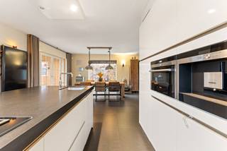 Deze instapklare woning is gelegen vlakbij de Nederlandse grens, op een zuidoost perceel van ca. 908 m². Het pand omvat oa. 3 slaapkamers, een badkamer, zolderruimte (4de slaapkamer), bijgebouw bestaande uit garage, studio en kelder.<br /><br />Indeling:<br />Gelijkvloers:<br />Centrale inkomhal met gastentoilet verleent toegang tot de woonkamer. De volledig geïnstalleerde keuken is voorzien van Miele toestellen (een gaspitvuur, een vaatwasser, een quooker, een ijskast, een oven, een inbouw koffieapparaat, combi micro/oven, oven) en afgewerkt met een natuurstenen werkblad. Verder is er nog een achterinkom, dewelke momenteel ingericht is als bureauruimte.<br />De kelderruimte betreft ca. 12m²<br /><br />Eerste verdieping:<br />Op deze verdieping situeren zich 3 slaapkamers, waarvan 1 geniet van een dakterras. De badkamer is ingericht met een inloopdouche, wastafel en een toilet. <br /><br />Tweede verdieping:<br />De zolderruimte is te bereiken via een vaste trap en deze is volledig afgewerkt en daardoor bruikbaar als 4de slaapkamer. De ruimte is volledig open, dit creërt de mogelijkheid om op te delen en zo een 5de slaapkamer te creëren.<br /><br />Tuin:<br />De tuin is georïenteerd naar het zuidoosten en ingericht met een overdekt terras achteraan de woning en een bijgebouw. Laatstvernoemde omvat op het gelijkvloers een garage en is op de eerste verdieping momenteel ingericht als woonst met keuken, slaapkamer met een ligbad en wastafel. Deze is eveneens volledig onderkelderd. <br />Naast het bijgebouw is nog een carport aanwezig.<br /><br />Buitengewone kenmerken:<br />- Instapklaar en afgewerkt met hoogwaardige materialen<br />- EPC label B<br />- Bijgebouw met woonst en kelder<br />- Mogelijkheid tot het creëren van 5 slaapkamers<br />- Vlakbij de Nederlandse grens