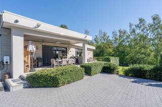 Century21 ImmoNero presenteert deze prachtig gerenoveerde bungalow woning van 221m² met uitzonderlijke afwerking, in een schitterende parktuin van 3.771m² welke u absolute rust en privacy waarborgt Via de electrische toeganspoort komt u het domein binnen langs de brede, verlichte privéoprit met een 6 tal parkeerplaatsen. De bungalow welke zeer grondig en volledig werd vernieuwd in 2020 -2025 biedt vervolgens: Inkom met WC, schitterende living met hypergeinstalleerde keuken van 78m², welke naadloos doorloopt in de prachtig aangelegde terrassen met subliem zicht op de parktuin; Ingerichte wasplaats 7m² en 2 kinderkamers van elk 12m² met ingemaakte kasten, Douchekamer; Masterbedroom bestaande uit Ingerichte dressing, kamer 26m² en en suite badkamer. Grote garage van 21m², Carport voor 2 wagens en tuinberging. Verwarming met Warmtepomp, zonnepanelen en Airco in alle ruimtes. Alu ramen, ventilatie D, Laadpaal, Camerabewaking rondom, Electriciteit is conform. EPC = B