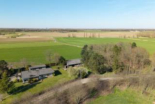 Meer info en bezoeken: 0485/321.842<br />Gelegen tegen de grens met Nederland en in het prachtige polder- en krekengebied, geniet deze eigendom van een uitzonderlijk mooie ligging. Op zo'n 4km buiten de centra van Wachtebeke en Zelzate bevindt zich deze woning met bijgebouwen. De woning en het magazijn werden gebouwd in 1965-66, de garage volgde kort nadien. De woning en de tuin hebben een zeer goede staat van onderhoud. Ondanks de ouderdom van het gebouw is zowel het interieur als het exterieur steeds met veel zorg onderhouden. De bouwtechnische staat is ook nog zeer goed, al zullen renovaties van o.m. het dak, isolatie, technieken en sanitair zich opdringen. Met een bewoonbare oppervlakte van 217m2 en met 4 slaapkamers is de woning ook nog steeds hedendaags wat de indeling betreft. De kamers zijn ruim, er is meer dan voldoende bergruimte en de leefruimtes zijn gericht naar de zonnekant. De garage achter de woning is zo'n 75m2, het magazijn heeft een oppervlakte van 250m2 en ook een praktische hoogte. Een groot voordeel is dat deze gebouwen nooit een landbouwfunctie hadden en ze dus ook reeds als een woning en woningbijgebouwen gekend zijn. De bestemming van de percelen is valleigebied, dit houdt in dat er mag verbouwd worden binnen het bestaande volume, maar slopen en heropbouwen en uitbreiden worden hier uitgesloten. een prachtig project voor mensen die op zoek zijn naar rust ruimte, natuur en nuttige oppervlakte!