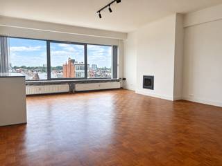 Op een toplocatie, praktisch in de achtertuin van het KMSKA, bevindt zich dit charmante appartement op de zevende en tevens hoogste verdieping. Met winkels, gezellige horeca en musea op wandelafstand en een vlotte verbinding met de belangrijkste invalswegen geniet u hier van een ideale locatie. <br /><br />U betreedt het appartement via een aparte inkomhal. Aansluitend bevindt zich een praktische berging met aansluiting voor wasmachine en droogkast.<br /><br />Vanuit de inkomhal bereikt u de open en lichtrijke leefruimte, afgewerkt met authentieke blokjesparket. De werkende houtkachel vormt een gezellige blikvanger en zorgt voor extra sfeer tijdens de koudere maanden. Dankzij de grote raampartijen en de ligging op de zevende verdieping geniet u bovendien van een prachtig panoramisch uitzicht over de stad.<br />De open keuken sluit mooi aan bij de leefruimte en is volledig uitgerust met kwalitatieve toestellen.<br /><br />De badkamer beschikt over een ruime douche en krijgt dankzij de speelse, karaktervolle tegels een unieke uitstraling.<br /><br />Aan de rustige achterzijde van het appartement bevinden zich twee slaapkamers. De master slaapkamer is voorzien van praktische ingebouwde kasten. Beide slaapkamers bieden rechtstreeks toegang tot het terras, waar u geniet van een bijzonder uitzicht op het Museum.<br /><br />Gemeenschappelijke kosten: 135 Euro per maand <br />Provisie gas en water: 85 Euro per maand<br />nutsvoorziening elektriciteit zijn privé op te nemen door de huurder.<br /><br />Onmiddellijk beschikbaar.