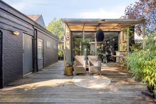 <p><strong>Halfopen woning met 3 slaapkamers, ruime tuin, garage en uniek tiny house nabij de Kalmthoutse Heide.</strong><span></span></p>
<p>Midden in het groen en vlak bij de prachtige Kalmthoutse Heide ligt deze charmante halfopen woning met een bewoonbare oppervlakte van ca. 148 m² op een perceel van ca. 800 m². Een woning die niet alleen veel wooncomfort biedt, maar dankzij de ruime tuin, garage en het aanwezige tiny house ook bijzonder veelzijdig is.</p>
<p>De woning ligt wat verder naar achteren op het perceel en is bereikbaar via 2 toegangspoorten. Aan de voorzijde is er een ruime oprit met plaats voor 2 wagens en een oplaadpunt voor een elektrische auto. Hier bevindt zich ook een tuinhuis dat uitstekend dienst kan doen als fietsenberging. Naast de woning staat een aparte garage met bijkomende berging.</p>
<p>Binnen word je verwelkomd in de inkomhal met ingemaakte vestiairekast. De gezellige leefruimte is afgewerkt met parket en sluit aan op een aparte bibliotheek. Dankzij de schuifdeur kan deze ruimte volledig worden afgesloten, waardoor ze ook interessant is als rustige werk- of hobbyruimte.</p>
<p>Verder bevinden zich op het gelijkvloers een gastentoilet en een praktische berging met aansluiting voor de wasmachine en de technieken.</p>
<p>Het hart van de woning is de ruime leefkeuken met eethoek en pelletkachel. De keuken is voorzien van een grote kookplaat met dampkap, vaatwasser, anderhalve spoelbak, stoomoven, microgolfoven, oven en koelkast. Via een schuifdeur stap je vanuit de leefkeuken rechtstreeks de tuin in. De achterinkom wordt momenteel als hoofdingang gebruikt.</p>
<p>Via de trap in de hal bereik je de eerste verdieping. Hier bevinden zich 3 slaapkamers en de badkamer. Eén slaapkamer is momenteel ingericht als dressing, maar kan perfect opnieuw als slaapkamer worden gebruikt. De hoofdslaapkamer beschikt over ingebouwde kasten. De badkamer is ruim uitgerust met een bad, aparte douche, toilet en dubbele lavabo met meubel.</p>
<p>Ook buiten heeft deze woning heel wat te bieden. De tuin is volledig omheind en achter de woning zijn 2 gezellige terrassen aangelegd. Een absolute blikvanger is het tiny house in de tuin. Dit wordt momenteel gebruikt als extra werkplek. Er is bovendien ruimte voorzien voor het plaatsen van een toilet, douche en lavabo, waardoor het tiny house verschillende gebruiksmogelijkheden biedt.</p>
<p>Ook op technisch vlak zijn er interessante troeven. De woning wordt verwarmd op aardgas via radiatoren en in de keuken is aanvullend een pelletkachel aanwezig. In 2023 werd een Bosch 7000i 35C condensatieketel geplaatst. Het schrijnwerk op het gelijkvloers werd in 2020 vernieuwd en uitgevoerd in PVC. Daarnaast zijn er 7 zonnepanelen en een elektrisch oplaadpunt aanwezig.</p>
<p>Een woning voor wie houdt van groen, ruimte en flexibiliteit, met de Kalmthoutse Heide vlakbij en extra mogelijkheden dankzij de garage, ruime tuin en het bijzondere tiny house.</p>
<p>BEZOEKMOMENT: zaterdag 10 oktober tussen 10u en 12u (na afspraak).<br />Voor meer info of een bezoek te plannen, surf naar www.putsesteenweg61.be!</p>