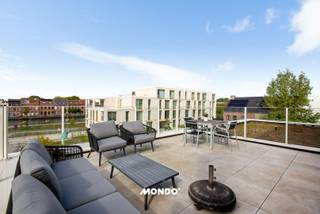 Dans un endroit agréable à Willebroek se trouve cet appartement lumineux et modernement aménagé avec 2 chambres, une terrasse spacieuse et une vue magnifique sur le canal.<br /><br />Par le hall d'entrée, avec de l'espace pour un vestiaire, vous accédez aux différentes pièces de l'appartement. Le salon forme le cœur de la maison et bénéficie d'une grande luminosité naturelle grâce aux grandes baies vitrées. Le salon se connecte joliment à la salle à manger et à la cuisine ouverte et moderne.<br /><br />La cuisine est aménagée de façon élégante et contemporaine et dispose d'un îlot central avec des sièges. Adjacent au salon se trouve la terrasse spacieuse, où vous pourrez profiter en toute tranquillité de la vue dégagée sur l'eau et les environs.<br /><br />L'appartement dispose de deux chambres à coucher complètes. La plus grande chambre bénéficie à nouveau d'une belle luminosité grâce aux fenêtres du sol au plafond et offre suffisamment d'espace pour un grand lit et des armoires supplémentaires. La deuxième chambre est également spacieuse et peut parfaitement servir de chambre d'enfant, d'invité ou de bureau.<br /><br />La salle de bains est moderne et équipée à la fois d'une baignoire et d'une douche à l'italienne séparée. Les grands carreaux de mur et de sol donnent une apparence soignée et intemporelle.<br />Dans tout l'appartement, la finition contemporaine se démarque, avec une combinaison de parquet dans les espaces de vie et de couchage et de carrelage facile d'entretien dans le hall et la salle de bains. Les grandes fenêtres, les couleurs neutres et l'agencement ouvert créent une sensation d'espace particulièrement agréable.<br /><br />Un bel appartement prêt à emménager pour ceux qui recherchent un logement confortable avec beaucoup de lumière, d'espace extérieur et une vue exceptionnellement dégagée.<br /><br />Intéressé ou envie d'une visite sur place?<br />Contactez directement Bjorn<br />📞 +32 477 60 68 33<br />Mail: bjorn@mondovastgoed.be