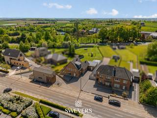 Voor meer info en foto’s, surf naar www.swevers.be – Tongersesteenweg 98 in Tongeren-Borgloon is een instapklare woning met veel ruimte, een praktische indeling en interessante mogelijkheden voor de toekomst. De woning werd gebouwd in 1958 en biedt een ruime bewoonbare oppervlakte van 265 m² op een perceel van 18a 65ca. Op het gelijkvloers vind je een aangename leefruimte met woonkamer van 34,11 m², aansluitend op de eetkamer en de keuken van 17,80 m². De indeling zorgt voor een vlotte verbinding tussen wonen, koken en eten. Daarnaast zijn er een berging en wasruimte aanwezig. Een grote troef is de slaapkamer van 17,36 m² op het gelijkvloers. Hierdoor is de woning geschikt voor wie gelijkvloers wil slapen of werken, maar ook voor wie denkt aan kangoeroewonen of een zorggerichte woonoplossing. Op de eerste verdieping bevinden zich nog drie slaapkamers van 17,21 m², 12,50 m² en 12,10 m², samen met de badkamer. De zolder en kelder van 30,11 m² zorgen voor bijkomende opslagruimte of mogelijke extra invulling. Buiten geniet je van een ruim perceel met plaats om te ontspannen, te tuinieren of kinderen te laten spelen. De 35 zonnepanelen vormen een extra pluspunt voor wie energiezuinig wil wonen. Ook de ligging is praktisch: winkels, scholen, bushalte en ontspanning bevinden zich vlakbij, met vlotte verbindingen naar station en snelweg. Deze woning combineert vier slaapkamers, veel bergruimte, een groot perceel en toekomstpotentieel op een bereikbare locatie. Voor meer informatie, bel 012 699 900. Bron bewoonbare oppervlakte: EPC – verslag.