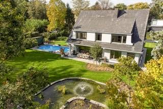 <p>Op een rustige en residentiële locatie, in een doodlopende straat, bevindt zich deze ruime villa op een mooi perceel van ca. 2.088 m².</p>
<p><span>De recent volledig heraangelegde tuin met vijver en zwembad biedt bijzonder veel privacy en vormt een aangename omgeving om in alle rust te genieten.</span></p>
<p><span>Een mooie combinatie van ruimte, privacy en een uitstekende ligging.</span></p>
<h3><span><br />Indeling</span></h3>
<p><strong><span><br />Gelijkvloers</span></strong></p>
<p><span>De royale inkomhal geeft toegang tot de leefruimte, die is ingedeeld in een eetkamer en een salon met open haard en bar.</span></p>
<p><span>De volledig geïnstalleerde keuken is voorzien van alle hedendaags comfort. Zowel vanuit de keuken als de leefruimte geniet men van een mooi zicht op de tuin, die bovendien rechtstreeks toegankelijk is.</span></p>
<p><span>Het overdekte terras sluit dankzij de grote schuiframen mooi aan op de leefruimte en vormt een aangename uitbreiding van het woongedeelte. Hierdoor kan men hier in elk seizoen comfortabel vertoeven.</span></p>
<p><span>Verder beschikt het gelijkvloers over een gastentoilet, een dubbele inpandige garage met aansluitende wasplaats en toegang tot de kelder met stahoogte.</span></p>
<p><strong><span><br />Verdieping</span></strong></p>
<p><span>De overloop geeft toegang tot vijf slaapkamers, waaronder een bijzonder royale hoofdslaapkamer. Twee van de overige slaapkamers zijn voorzien van een eigen lavabo.</span></p>
<p><span>De ruime badkamer beschikt over een dubbele wastafel, ligbad en afzonderlijke douche. Op de nachthal bevindt zich tevens een apart toilet.</span></p>
<p><strong><span><br />Zolder</span></strong></p>
<p><span>De zolderverdieping is bereikbaar via een uitschuifbare trap en biedt, indien gewenst, mogelijkheden tot verdere uitbreiding.</span></p>
<h3><span><br />Tuin</span></h3>
<p><span>De recent heraangelegde tuin geniet van bijzonder veel privacy en is voorzien van een vijver, zwembad en aansluitend zonneterras. De verzorgde tuinaanleg met beregeningssysteem maakt het geheel compleet.</span></p>
<h3><span><br />Bijzonderheden</span></h3>
<p><span>Rustige ligging in een doodlopende straat<br /></span><span>Verwarming op mazout<br /></span><span>Houten ramen met dubbele beglazing<br /></span><span>Overdekt terras<br /></span><span>Recent vernieuwde tuinaanleg met beregeningssysteem<br /></span><span>Zwembad met zonneterras<br /></span><span>EPC-label D – 394 kWh/m² – UC 2597369<br /></span><span>Elektrische installatie niet conform</span></p>
Vg-Wp-Vv-Gvkr-Gmo-Gworg