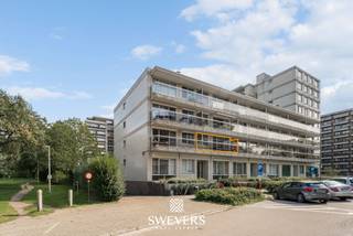 Voor meer info en foto’s, surf naar www.swevers.be – Aan Casterstraat 60 bus 4 in Hasselt bevindt zich dit op te frissen appartement met een bewoonbare oppervlakte van 92 m². Dankzij de centrale ligging woon je vlak bij het centrum, met winkels, openbaar vervoer, restaurants en scholen op wandelafstand. Het cultureel centrum ligt bovendien recht tegenover het gebouw. Het appartement dateert van 1977 en is bereikbaar met de lift. Het appartement beschikt over een gunstig EPC-label van B. De ruime woonkamer en eetkamer genieten dankzij grote raampartijen van veel natuurlijke lichtinval en geven toegang tot een breed terras aan de voorzijde. Aansluitend bevindt zich een afzonderlijke keuken. Aan de andere zijde liggen twee volwaardige slaapkamers, die beide toegang bieden tot een tweede terras. Verder beschikt het appartement over een badkamer en een apart toilet. De huidige staat biedt volop mogelijkheden om keuken, badkamer en afwerking volledig naar eigen smaak te vernieuwen. Extra praktisch zijn de beveiligde inkomdeur, een kelderberging van 3 m² en parkeermogelijkheid voor de deur. Met twee slaapkamers, twee terrassen en een ruime, lichtrijke leefzone vormt dit appartement een interessante basis voor wie op zoek is naar ruimte én renovatiemogelijkheden op een centrale locatie in Hasselt. Voor meer informatie, bel 011 255 155. Bron bewoonbare oppervlakte: EPC – verslag.