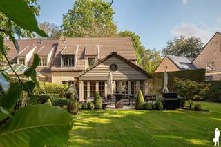 <p><strong><span>Stijlvolle koppelvilla met 5 slaapkamers en prachtige tuin op ca. 1.033 m² in exclusief afgesloten woondomein "Dennenburg"!</span></strong></p>
<p><span>Deze sfeervolle </span><strong><span>koppelvilla</span></strong><span> combineert royale woonvolumes met een bijzonder groene woonomgeving. Met </span><strong><span>5 slaapkamers, 2 badkamers, een inpandige garage</span></strong><span> en een indrukwekkende leefkeuken biedt de woning alle ruimte voor comfortabel gezinsleven. Grote raampartijen zorgen voor veel licht en een prachtige tuinconnectie.</span></p>
<p><strong><span>Gelijkvloerse verdieping</span></strong><br /><span>- </span><strong><span>Inkomhal</span></strong><span> met ingemaakte vestiairekasten en gastentoilet</span><br /><span>- Royale </span><strong><span>woon- en eetkamer</span></strong><span> op parket met grote raampartijen en maatwerk</span><br /><span>- Ruime </span><strong><span>leefkeuken</span></strong><span> met kook- en spoeleiland en veel bergruimte</span><br /><span>- Aparte eetruimte met zicht op de tuin</span><br /><span>- Hoge houten plafondstructuur en grote glaspartijen</span><br /><span>- Rechtstreekse toegang tot terras en tuin</span><br /><span>- Afzonderlijk </span><strong><span>bureau</span></strong><span> met maatwerk</span><br /><span>- Toegang tot de </span><strong><span>inpandige garage</span></strong></p>
<p><strong><span>Eerste verdieping</span></strong><br /><span>- Nachthal</span><br /><span>- Verschillende ruime slaapkamers</span><br /><span>- </span><strong><span>Mastergedeelte met royale dressing. Badkamer met ligbad en dubbele wastafel</span></strong><br /><span>- Badkamer met </span><strong><span>inloopdouche en lavabomeubel</span></strong></p>
<p><strong><span>Tweede verdieping</span></strong><br /><span>- Ruime slaapkamer onder het dak met zichtbare balken</span><br /><span>- Eveneens geschikt als hobby- of werkruimte</span></p>
<p><strong><span>Tuin en buitenruimte</span></strong><br /><span>- Perceel van ca. </span><strong><span>1.033 m²</span></strong><br /><span>- </span><strong><span>Zuidwestgerichte</span></strong><span>, fraai aangelegde tuin</span><br /><span>- Veel groen en privacy dankzij volwassen bomen en hagen</span><br /><span>- Ruim terras en royale gazonpartijen</span><br /><span>- Oprit met parkeergelegenheid</span></p>
<p><strong><span>Garage en berging</span></strong><br /><span>- </span><strong><span>Inpandige garage</span></strong><br /><span>- Praktische berging en zolderruimte</span></p>
<p><strong><span>Bijzonderheden</span></strong><br /><span>- </span><strong><span>5 slaapkamers en 2 badkamers</span></strong><br /><span>- Veel maatwerk en ingemaakte kasten</span><br /><span>- Apart bureau</span><br /><span>- Verwarming op aardgas</span><br /><span>- EPC </span><strong><span>187 kWh/m² – label B</span></strong><br /><span>- Exclusief </span><strong><span>afgesloten woondomein</span></strong></p>
<p><strong><span>Ligging</span></strong><br /><span>Gelegen</span><span> binnen het exclusief afgesloten woondomein </span><strong><span>Dennenburg</span></strong><span>. Een groene en residentiële omgeving met veel rust en privacy, op vlotte afstand van winkels, scholen en dagelijkse voorzieningen. Ook Kapellen en Kalmthout zijn vlot bereikbaar.</span></p>
<p><strong><span>Een stijlvolle gezinswoning met royale woonvolumes en een prachtige tuin binnen een exclusieve, groene woonomgeving.</span></strong></p>