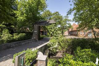 <strong>Uniek gelegen eigendom 'domein 'Klein Hoef'', gekend als de oudste hoeve van Retie, nabij centrum en uitstekend commercieel doch natuurlijk-groen gelegen aan de Retiese ring richting Kasterlee/Oud-Turnhout en nabij de Nederlandse grens. Het onroerend goed, gelegen op een perceel van maar liefst 11.465m² bestaat uit (i) een ruime zaak (ca. 500m²) waarin thans klassebrasserie 'De Klynhoeve' is gevestigd (handelshuur eindigt 2028), (ii) een woning met riant stalgebouw voor opslag (totaal ca. 340m²), en (iii) enkele bijgebouwen (oude stal achteraan, overdekte opslag vooraan). </strong><br /><br /><strong>Het geheel biedt een unieke kans voor ondernemers/investeerders die dromen van een bloeiende horecazaak met riante woongelegenheden. Het eigendom biedt tal van mogelijkheden gelet op de verschillende gebouwen en de private ligging; bovendien omgeven door uitgestrekte natuurbossen (onder meer richting Groendomein Prinsenpark) en verschillende fiets- en wandelroutes. Er is een energielabel D voor woonhuis met stal (geen renovatieverplichting) en een label G voor de brasserie. </strong><br /><br /><span>Dit uitzonderlijke vastgoedgeheel dient gerenoveerd te worden (o.a. elektriciteit, renovatie woning, aanleg tuin). </span><br /><br /><span>Aangrenzend zijn er legio parkeermogelijkheden en liggen enkele hectaren grond die tevens aangekocht kunnen worden: info op aanvraag.<br /><br /></span><strong></strong><span>Algemeen</span><strong>:<br /></strong>Aan de Kleine Nete gelegen omwalde hoevesite met een eeuwenoude oorsprong; de oudste bronnen vermelden het hoevecomplex reeds begin 16e en midden 17e eeuw. De hoeve met bijgebouwen zoals deze thans doorgaat bestaat sinds begin 20ste eeuw uit losstaande bestanddelen, rondom een erf geschikt: een woonstalhuis (nok loodrecht op de straat), een parallel gelegen schuur met bijschuurtje waarin thans Brasserie 'Klynhoeve' wordt uitgebaat, een toegangspoort.<br /><br />De hoevesite met oud grachtensysteem werd in de 20ste eeuw verder uitgewerkt en geïntegreerd in het nieuwe kasteeldomein; de hoeve diende een bloeiend landbouwbedrijf te worden dat het kasteel en ook de dorpelingen voorzag van groenten, fruit, melk en vlees. Zo kreeg de 'Klein Hoef' een gestructureerde aanleg met een moestuin, een omgrachte kleine en grote boomgaard, en een essenbos. De eiken van de Grote Dreef en andere aanplantingen langs de grachten vormden een natuurlijk scherm tussen park en hoevesite.<br /><br /><span>Horecazaak (brasseriegebouw)</span>:<br />Van de huidige hoevegebouwen zijn de monumentale schuur en toegangspoort de oudst bewaarde. Het huidige hoofdschuurvolume is ca. 1992 sterk verbouwd en gerenoveerd tot café-brasserie. Dit gebouw bestaat uit een verbruikzaal, keuken, opslag en wintertuin; er is verder ook een terras aanwezig. Een suggestie van het de binnenkant/het interieur van de brasserie kunt u bekijken via de website van de brasserie (https://deklynhoeve.be/).<br /><br />Het handelsfonds is niet mee over te nemen - handelshuur eindigt in 2028: informatie op aanvraag.<br /><br /><span>Woongedeelte en stallingen</span>:<br />Van het oorspronkelijk woonstalhuis werd in 1952 de stal en in 1963 ook het woonhuis vervangen door de huidige. Deze delen van het onroerend goed verdienen een totaalrenovatie. Voor de bouw van het woonhuis zijn evenwel degelijke materialen gebruikt: arduinen dorpels, dak in rode pannen, houten ramen en kornissen.<br /><br />De woning beschikt over een ruime zitplaats en leefruimte. Er zijn 4 slaapkamers voorzien en een riante zolder. De woning is tevens onderkelderd (kleine provisiekelder - niet droog). De aan de woning aansluitende stalling beschikt over ca. 215m² extra aan stal-/opslagruimte; en biedt zo legio feitelijke mogelijkheden naar invulling toe. Er is gasaansluiting aanwezig.