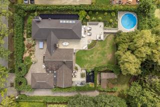 <strong><span>Exclusieve laagbouwvilla op 2.191m² met 4 slpk / 3 bdks en binnen-en buitenzwembad</span></strong><br /><br />Zeer rustig gelegen in een residentiële buurt grenzend aan het Zoerselbos bevindt zich deze uitzonderlijke villa met hoogstaande afwerking en een waaier aan luxevoorzieningen, ingericht door Joris Van Apers.<br /><br />Geniet van ultiem wooncomfort op een prachtige locatie, waar ruimte, ontspanning en verfijning samenkomen. De woning onderging grondige renovaties en uitbreidingen in zowel 1998 als 2010. <br /><br />Inkomhal met toegang tot de ruime L-vormige woonkamer (45m²) op Italiaanse eiken parket met een massieve handgemaakte schouw. Gastentoilet op exclusieve Azul Bahia granieten vloer. <br /><br />De leefkeuken (37m²) is een absolute eyecatcher: een semi-professionele ruimte, uitgerust met o.a. een teppanyaki, wok, friteuse, inductiekookplaat met vijf zones, dubbele dampkappen, professionele kraan, dubbele spoelbak, stoomoven, twee heteluchtovens, een koelcel, twee wijnkoelers, een ontbijttoog en een vermaler. Het werkblad is in stijlvol Marbrinoise. <br /><br />De biljartkamer (39m²) of extra woonkamer op Bourgondische natuursteen is uitgerust met high-end muurbekleding, een open haard en oude Spaanse kasteeldeuren. Deze ruimte is tevens geschikt als praktijkruimte. <br /><br />Via de royale nachthal bereikt u een aparte wasruimte, een vernieuwde badkamer met losstaand ligbad, wastafel, handdoekdroger en 4 slaapkamers. <br />Slpk 1 (18m²) op parket in Italiaanse notelaar met dressing, ensuite badkamer (2010: dubbele wastafel, ligbad, toilet, handdoekdroger) én directe toegang tot een ontspannend en afgesloten terras met vijver en verschillende fonteinen. <br />Slpk 2 (16m²) op parket met dressing en ensuite badkamer met toilet, inloopdouche, wastafel en handdoekdroger. <br />Slpk 3 (14m²) en slpk 4 (18m²) zijn afgewerkt met parket, waarbij slaapkamer 4 beschikt over een ingemaakte kast. <br /><br />Deze villa beschikt over een ruim binnenzwembad met directe toegang via schuifdeuren tot het terras, waar elektrische verwarming en zonnetenten voor extra comfort zorgen. Aansluitend aan het zwembad bevindt zich een wellnessgedeelte met sauna, douche en toilet. <br /><br />Prachtige aangelegde tuin met buitenzwembad en meerdere terrassen. Het perceel is volledig omheind en toegankelijk via een automatische poort. Er zijn meerdere autostaanplaatsen voorzien langs een verlichte oprit, alsook een werkplaats/schuur met zwembad- en vijverinstallatie. <br /><br /><span>Extra:</span> <br />* EPC B <br />* 30 zonnepanelen (2021) met batterij <br />* Warmtepomp buitenzwembad (2025) <br />* CV op stookolie (2012) <br />* Diverse bergzolders <br />* Hobbykelder (66m²) <br />* Drie elektrische zonnetenten <br />* Openhaardschouwen met afzuiging, blaasbalg en timer (rookvrij) <br />* Inbraakwerend dubbel gelaagd dubbele beglazing <br /><br />Elektrische keuring en asbestattest in aanvraag.