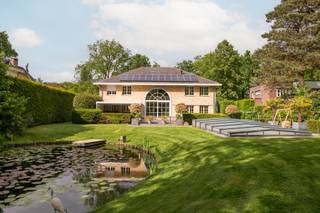 Deze uitzonderlijk ruime Amerikaanse luxevilla, gelegen op wandelafstand van het centrum van Heide, biedt een zeldzame opportuniteit voor de zelfstandige ondernemer of het een gezin op zoek naar ruimte, comfort en kwaliteit.<br /><br />De villa verkeert in uitstekende staat en werd met oog voor detail afgewerkt met hoogwaardige materialen door de hele woning.<br />Men betreedt de woning via een grote inkomhal op natuursteen, met een vestiare ruimte leidt tot en een gastentoilet met lavabo. De lichtrijke leefruimte, eveneens op natuursteen, omvat een elegante zithoek en een eetkamer, gescheiden door een sfeervol tweezijdige gashaard. Een tweede zithoek op parket vervolledigt dit warme geheel — de ideale plek voor het gezin om samen te komen.<br /><br />Aansluitend aan de eetkamer bevindt zich de volledig uitgeruste keuken met alle toestellen en zicht op de tuin. Dankzij haar royale afmetingen biedt de keuken bovendien ruimte voor een gezellige eettafel — het kloppend hart van de woning.<br /><br />Op het gelijkvloers is verder een ruime slaapkamer op parket met ensuite badkamer (douche, lavabo en toilet), een praktische zijdeur en toegang tot de kelder. en naar de tuin . Deze kamer leent zich uitstekend als gastenkamer of au-pair verblijf.<br /><br />De trap in de inkomhal leidt naar de eerste verdieping, waar een spectaculaire, lichtrijke overloop met mezzaninegevoel boven de eetkamer de verdieping bepaalt — ideaal als extra zithoek, speelruimte of thuiskantoor. Op deze verdieping bevinden zich drie slaapkamers, elk voorzien van airconditioning, en een gedeelde badkamer met ligbad, douche, lavabo en toilet.<br /><br />De hoofdslaapkamer beschikt over een luxueuze ensuite badkamer met jacuzzi ligbad, douche en dubbele lavabo, en grenst aan een royale inloopdressing met ingebouwde kasten en Laden .<br /><br />Via een vaste trap bereikt men de zeer ruime zolder, momenteel ingericht als kantoor. Achter een wand bevindt zich bovendien een grote bergzolder met bijkomend integratiepotentieel — of extra speelruimte voor de kinderen.<br /><br />De volledige kelderverdieping van ca. 200 m² herbergt een technische ruimte, werkplaats, wasruimte, extra berging én een sport ruimte plus een indrukwekkende garage met plaats voor meerdere wagens.<br /><br />De villa is gelegen op een prachtig, zuidgericht open perceel. De tuin beschikt over een deels overdekt terras met zicht op een sierlijke vijver, een verwarmd zwembad met automatische overkapping en een tuinhuis met extra opslagruimte.<br /><br />Deze villa ligt langs een mooie laan in Heide-Kalmthout. Het gezellige centrum ligt op wandelafstand, met alle nodige voorzieningen binnen handbereik. Het station biedt een vlotte verbinding naar Antwerpen, Brussel en Nederland.