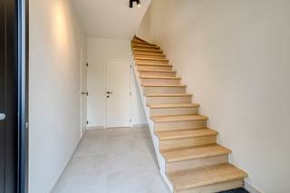 <p><strong>Energiezuinige en lichtrijke halfopen bebouwing</strong> met een bewoonbare oppervlakte van ca. 190 m², 4 slaapkamers, parkeerplaats en omringd door groen. Het betreft de <strong>eerste ingebruikname</strong> van de woning (nieuwbouw).</p>
<p><strong>Indeling:</strong><br /><span><em>Gelijkvloers</em><em>:</em></span><br />U betreedt de woning via de ruime inkomhal met apart toilet en vervolgens komt u in een uitgestrekte, lichtrijke ruimte met bureau-, zit- en eetgedeelte met hoogwaardige open keuken met keukeneiland. De volledig uitgeruste keuken geniet alle comfort: een kookeiland en kwaliteitsvolle toestellen. Er is meer dan voldoende kastruimte, een dubbele inox gootsteen, een inductievuur met ingewerkte dampkap, combi-oven, oven, vaatwasser, koelkast, diepvries en een eiland met een inductievuur inclusief ingewerkte dampafzuiging. De keuken vormt een passend geheel met de leefruimte, die naadloos aansluit op de uitgestrekte tuin met terras (heden in aanleg). Achteraan bevindt er zich een praktisch tuinhuis met een overkapping, dienstig als loungegedeelte. Naast de keuken bevindt er zich nog een praktische technische berging met wasaansluiting.</p>
<p><span><em>Eerste verdieping:</em></span><br />De nachthal op de eerste verdieping sluit aan op twee ruime slaapkamers met ingemaakt kasten van 13m². De badkamer is luxueus afgewerkt met inloopdouche met regendouchekop, spiegel, handdoekradiator en wastafel met kastgedeelte. Op de nachthal is er ook een apart toilet voorzien.</p>
<p><span><em>Tweede verdieping:</em></span><br />Hier bevinden zich twee slaapkamers en een badkamer met ligbad, wastafel en spiegel met verlichting.</p>
<p>De woning geniet overal dezelfde verfijnde en kwalitatieve afwerking. Er is één privatieve parkeerplaats voorzien.</p>
<p><strong>Bijzonderheden:<br /></strong>Voldoende parkeergelegenheid;<br />Hoogwaardige nieuwbouw;<br />Vloerverwarming;<br />EPB in opmaak.<br /><br /><strong>Ligging:</strong><br />Gelegen in een<strong> residentiële woonwijk</strong> met veel jonge gezinnen, nabij invalswegen en winkels.</p>