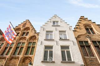 This elegant townhouse, fully renovated in 2018, seamlessly combines timeless elegance with modern living comfort. It features a unique Japanese-inspired city garden with a covered water terrace, offering an exceptional living experience in the heart of Bruges' prestigious "Golden Triangle."<br /><br />Layout<br />Ground floor:<br />Upon entering, you are welcomed by a spacious entrance hall with a cloakroom and guest toilet. The bright living area boasts high-quality parquet flooring and a modern gas fireplace. A centrally located patio enhances natural light and creates a subtle separation from the fully equipped kitchen, which includes a generous dining area and offers a stunning view of the serene city garden.<br /><br />Basement level:<br />An open staircase leads to a stylishly designed living space (Cave) with underfloor heating and authentic vaulted ceilings, directly connected to the exclusive covered water terrace. This level also includes a guest toilet, a spacious storage room, a laundry room, and a practical bicycle storage area.<br /><br />First floor:<br />This floor comprises two spacious bedrooms, one of which features a dressing room. Each bedroom has its own fully equipped bathroom. Additionally, there is a separate toilet and a night hall with built-in wardrobes.<br /><br />Second floor:<br />The top floor is accessible via two separate staircases. At the rear, one staircase leads to a comfortable guest room, while at the front, a second staircase opens onto a spacious and charming bedroom with a mezzanine, as well as an open office space with built-in wardrobes.<br /><br />Key Features<br />✔ Fully renovated in 2018<br />✔ Living area: 374 m²<br />✔ Prime location in Bruges' "Golden Triangle"<br />✔ Energy-efficient (EPC label B)<br />✔ Bright and spacious living areas