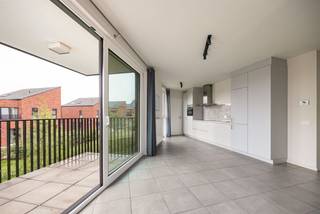 <p><span>Geen zin in verbouwen, schilderen of verrassingen? Dan zit je hier goed. Dit appartement uit 2017 ligt in een jonge woonwijk waar kinderen nog op straat spelen en buren elkaar kennen. Je woont hier rustig, met een supermarkt om de hoek, het Boekenbergpark vlakbij en een Velostation letterlijk voor de deur.</span></p><p><span> </span></p><p><span>Binnenkomen en je jas neergooien</span></p><p><span>De inkomhal is slim ingedeeld voor een vestiaire. Verderop opent het appartement zich meteen naar de leefruimte. Geen verloren vierkante meters hier, maar een logische indeling waarbij koken, eten en ontspannen mooi in elkaar overvloeien.</span></p><p><span>De woonkamer krijgt langs verschillende kanten daglicht binnen dankzij de hoekligging. Terwijl je aan tafel zit, kijk je uit op het groen en de jonge wijk rondom je. Geen gevel op twee meter afstand, maar een open gevoel dat je in veel appartementen mist.</span></p><p><span>De keuken houdt het strak en eenvoudig, met witte greeploze kasten, een inductiekookplaat, combi-oven, vaatwasser en flink wat opbergruimte. Achteraf verdwijnen de boodschappen gewoon in de aansluitende berging, zodat het werkblad netjes blijft.</span></p><p><span> </span></p><p><span>Koffie buiten, zelfs als het regent</span></p><p><span>Op het overdekte terras zit je beschut en toch buiten. Groot genoeg voor een tafeltje en enkele stoelen. Dankzij het vele groen in de omgeving voelt het hier verrassend rustig aan voor een locatie zo dicht bij de stad.</span></p><p><span>Verder zijn er twee slaapkamers. De grootste biedt voldoende plaats voor een dubbel bed en een ruime kast. De tweede kamer doet even vlot dienst als kinderkamer, bureau of dressing.</span></p><p><span>De badkamer kreeg een verzorgde, tijdloze afwerking met een ruime inloopdouche en een dubbel lavabomeubel. Geen ochtenddiscussies meer over wie eerst aan de wastafel staat.</span></p><p><span> </span></p><p><span>Praktisch wonen</span></p><p><span>Ook aan de minder zichtbare zaken werd gedacht. Er is een aparte plek voor wasmachine en droogkast, een ruime kelderberging voor spullen die je niet dagelijks gebruikt en een ondergrondse parkeerplaats die verplicht mee aan te kopen is. Thuiskomen en niet meer rondjes rijden op zoek naar een vrije plek: het lijkt een detail, tot je het gewoon bent.</span></p><p><span> </span></p><p><span>Jong, groen en verrassend goed verbonden</span></p><p><span>Deze buurt trekt vooral jonge gezinnen en starters aan. Kinderen spelen in de buurt, de speeltuin ligt vlakbij en voor een wandeling hoef je niet verder dan het Boekenbergpark. Met tram, bus, velo en de Ring vlakbij geraak je bovendien snel waar je moet zijn, zonder midden in de drukte te wonen.</span></p><p><span><br /><br /></span></p>