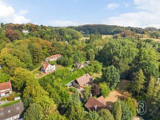 Aan de Oudestraat ontdekt u deze statige villa uit 1990, een karaktervolle woning waar ruimte, licht en groen centraal staan. De mooie volumes, grote glaspartijen en het veelvuldige gebruik van hout creëren een warme sfeer en geven de woning een heerlijk vakantiegevoel.Op het gelijkvloers leidt de inkomhal naar de royale leefruimte, waar de overvloedige lichtinval en het zicht op de tuin meteen in het oog springen. De gezellige zithoek met haard vormt het warme hart van de woning. Verder vindt u hier een aparte keuken met aansluitend een praktische, ruime berging, een bureau en een ruime garage. De later aangebouwde veranda is een absolute troef. Dankzij de grote glaspartijen geniet u hier volop van het omliggende groen en lopen binnen en buiten mooi in elkaar over.Op de eerste verdieping bevinden zich een badkamer en drie ruime slaapkamers met inbouwkasten. Eén van de kamers beschikt bovendien over een aangenaam terras met zicht op de groene omgeving.Buiten wacht een prachtige tuin met ruim gazon, bomen en weelderige beplanting. Een heerlijke plek die rust, privacy en een bijzonder gevoel van rust biedt. Daarnaast zijn er een tuinberging en een carport aanwezig voor twee wagens.De ligging combineert rustig en groen wonen met een vlotte bereikbaarheid nabij de invalswegen, en is gelegen op wandelafstand van het centrum van Ronse en de dagelijkse voorzieningen. De woning heeft EPC-label E en biedt mooie mogelijkheden om energetisch te optimaliseren en tegelijk naar eigen smaak te moderniseren.Wil je deze woning ontdekken? contacteer me op Caroline@immobeguin.be