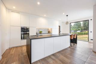 <p><strong>Hoogwaardig afgewerkte, recente en vrijstaande woning met o.a. 3 slaapkamers (mogelijkheid tot 4 of 5) en bijgebouw met tal van mogelijkheden op perceel van 1.112m² in Tielen. EPC: label A (61 kWh/m²). Elektriciteit conform.</strong></p>
<p><strong>Ligging:</strong> Centraal gelegen dicht bij het centrum van Tielen met een vlotte verbinding naar de omliggende gemeenten en E34.</p>
<p><strong>Indeling: 0:</strong> Inkomhal, apart toilet, bureau, open keuken, leefruimte, hal, wasplaats/berging <strong>+1:</strong> nachthal, slaapkamer 1 met dressing, slaapkamer 2, slaapkamer 3, dressing, badkamer, apart toilet <strong>+2:</strong> zolderverdieping <strong>buiten:</strong> terras, tuin, bijgebouw.</p>
<p><strong>Omschrijving:</strong></p>
<p>U betreedt deze vrijstaande woning via de inkomhal met apart toilet en trap naar de eerste verdieping. Vooraan bevindt zich de aparte bureauruimte die voorzien is van ingemaakte kasten en mogelijk biedt tot het ontvangen van klanten. Deze is toegankelijk via de inkomhal of via de keuken. De ruime leefruimte en open keuken geniet van veel natuurlijk lichtinval door de grote raampartijen die uitgeven op het terras en de tuin. Deze ramen zijn voorzien van zonwerende screens.</p>
<p>De hoogwaardige keuken is volledig uitgerust met koelkast, inductie kookplaat, ingebouwde dampkap, ingebouwde koffiemachine, combi-(stoom)oven, dubbele spoelbak, riant keukeneiland en uitzonderlijk veel kastruimte. Aansluitend bevindt zich de hal met veel ingemaakte kasten die toegang biedt naar de wasplaats/berging en naar de tuin.</p>
<p>Op de eerste verdieping bevindt zich de nachthal met apart toilet en de 3 slaapkamers, waarvan 1 met aansluitend een dressing. De 2 andere slaapkamers zijn ook voorzien van een gemeenschappelijke dressing die toegankelijk is via de nachthal. De slaapkamers zijn allemaal uitgerust met vliegenramen en verduisterende screens. De badkamer is uitgerust met inloopdouche, ligbad, dubbele wastafel en voldoende kastruimte.</p>
<p>De ruime zolderverdieping biedt tal van mogelijkheden en kan volledig worden ingericht volgens de wensen van de nieuwe eigenaar. Deze veelzijdige ruimte vormt een ideale basis voor het creëren van 1 of meerdere slaapkamers, een hobbyruimte, ontspanningsruimte, speelkamer… Er is ook nog een aparte technische berging aanwezig. De woning is energiezuinig o.a. door de aanwezigheid van ventilatiesysteem type D, 18 zonnepanelen en vloerverwarming.</p>
<p>Achteraan op het perceel bevindt zich een bijgebouw (140m²) met een brede waaier aan mogelijkheden, dat momenteel dienstdoet als garage. Het gebouw is op te frissen en bestaat uit een ruime kelder en een gelijkvloers met keuken, badkamer en apart toilet. Op de eerste verdieping bevinden zich nog 2 ruime kamers en een apart toilet.</p>
<p><strong>Bijzonderheden: </strong>aparte bureauruimte –<strong> </strong>ruime zolderverdieping – 18 zonnepanelen – ventilatie type D – ruime tuin – ruim bijgebouw</p>
<p><em>Bijzondere informatieplicht: in aanvraag</em></p>