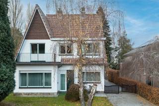 Deze charmante villa bevindt zich op een ruim perceel met een <strong>mooie parktuin</strong> en geniet van een <strong>uitstekende bereikbaarheid</strong> en zichtbaarheid. De combinatie van groen, privacy en een gunstige ligging maakt dit eigendom ideaal voor wie comfortabel wil wonen en eventueel wonen en werken wil combineren.<br /><br />Via de zijdelingse oprijlaan bereikt u de woning, met plaats voor meerdere wagens, een dubbele garage en een achterliggend magazijn. Zowel de voortuin als de afgesloten achtertuin zorgen voor een aangename buitenbeleving.<br /><br />Bij het betreden van de woning komt u in een ruime inkom- en traphal. Aan de voorzijde bevindt zich een bureauruimte met groot raam, ideaal als thuiswerkplek of praktijkruimte. De lichtrijke woonkamer beschikt over drie grote raampartijen en een elegante marmeren schouw met geïntegreerde houtkachel. Aansluitend vindt u de eetkamer, die via grote raam- en deurpartijen in verbinding staat met het terras en de tuin, en tevens toegang biedt tot de oprijlaan richting garage.<br /><br />De keuken sluit aan op de eetkamer en geeft toegang tot een gastentoilet en een wasplaats/technische ruimte met buitendeur.<br /><br />Op de eerste verdieping bevinden zich twee ruime slaapkamers en twee bijkomende kamers, evenals een badkamer met bad/douche, lavabo en toilet. De zolderverdieping, bereikbaar via een uitschuifbare trap, biedt extra bergruimte en potentieel.<br /><br />Deze woning vormt een mooie opportuniteit voor wie op zoek is naar een eigendom met karakter, ruimte en toekomstmogelijkheden in een groene, maar strategische omgeving.<br /><br /><u><strong>Voor meer info: kubra@ocvastgoed.be of 0465 08 41 48! </strong></u><br /><br />Bruto vloeroppervlakte (opgemeten volgens EPC) : 172 m<sup>2</sup> hoofdgebouw + 85 m<sup>2</sup> bijgebouw. <br /><br />Stedenbouwkundige inlichtingen: bouwvergunning, geen verkavelingsvergunning, woongebied met recreatieve karakter, geen voorkooprecht, geen gerechtelijke herstelmaatregel of bestuurlijke maatregel opgelegd.<br />Geen risicozone overstromingsgevoelig gebied. P-score = B, G-score = A,  <br />Elektriciteit niet conform <br />EPC: 813 kWh (F) <br />Renovatieverplichting