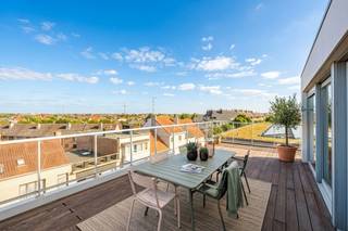 Ruimte, licht en een uitzonderlijk terras op een toplocatie. Dit prachtige duplex penthouse is gelegen op de 4de verdieping van de klassevolle residentie ‘Fusion’, een recente residentie uit 2008. Dankzij de centrale ligging bevinden winkels, openbaar vervoer, het strand en belangrijke invalswegen zich allemaal binnen handbereik.<br /><br />Met maar liefst 133 m² bewoonbare oppervlakte, drie slaapkamers en een riant, zonovergoten terras biedt dit penthouse een uitzonderlijk gevoel van ruimte en comfort.<br /><br />Bij het binnenkomen ervaar je meteen het WOW-effect. De bijzonder lichtrijke woonkamer baadt in het zonlicht en geniet rondom van terrassen, waardoor binnen en buiten hier perfect in elkaar overvloeien.<br /><br />De aangename parketvloer zorgt voor een warme en stijlvolle uitstraling. Er is voldoende ruimte voor een ruime zithoek en een aparte eetruimte, terwijl de grote keuken aansluit op de leefruimte en bovendien beschikt over een extra berging.<br /><br />De nachthal geeft toegang tot drie volwaardige slaapkamers, een badkamer met comfortabele inloopdouche en een apart toilet.<br /><br />Maar de absolute troef van dit penthouse is zonder twijfel het riante terras. Hier geniet je volop van de zon, de openheid en het mooie zicht rondom. Op heldere dagen reikt het zicht zelfs tot aan de zee in de verte. Een heerlijke plek om te ontbijten in de ochtendzon, lang te tafelen met vrienden of simpelweg te genieten van de rust en het uitzicht.<br /><br />De combinatie van de royale bewoonbare oppervlakte, de overvloedige lichtinval, de verschillende terrassen, drie slaapkamers en de uitstekende ligging maakt van dit duplex penthouse een bijzonder aangename woonst. Bovendien geniet je in deze recente residentie van een uitstekend EPC-label B en zijn er een gemeenschappelijke fietsenberging en afvalberging aanwezig.