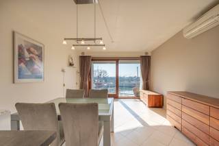 In Residentie Harbour View bevindt zich dit instapklare appartement met een prachtig uitzicht over de jachthaven. De lichtrijke leefruimte geeft uit op een zonnig terras aan de zuidkant, waar u in alle rust kunt genieten van het mooie uitzicht. De open keuken sluit naadloos aan op de leefruimte.<br />Het appartement beschikt over twee volwaardige slaapkamers, een badkamer met douche, een apart gastentoilet en een praktische berging. Daarnaast zijn er een privatieve staanplaats, een privatieve kelderberging en 2 fietshaken inbegrepen. Forfait syndickosten 50 euro/maand. Ref.OGA510