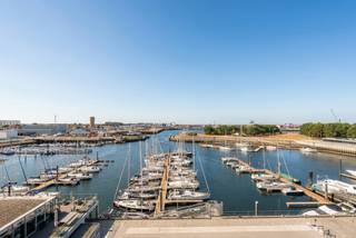 Op een gegeerde ligging aan de jachthaven van Zeebrugge bevindt zich dit stijlvol en luxueus afgewerkte appartement op de zesde verdieping van een zeer recente residentie. Met maar liefst 128 m² woonoppervlakte biedt het appartement een bijzonder aangenaam gevoel van ruimte en comfort.

De grote raampartijen zorgen voor een overvloed aan natuurlijk licht, terwijl de verschillende terrassen ervoor zorgen dat je doorheen de dag optimaal van de zon kunt genieten. Het zuidwestgerichte terras is dé plek om de dag af te sluiten met een prachtig zicht op de jachthaven.

Ook binnen werd aan elk detail gedacht. De ruime leefruimte met open keuken vormt het centrale hart van de woning. Daarnaast zijn er twee ruime slaapkamers, elk met een eigen badkamer, aangevuld met een dressing, ingemaakte kasten en een praktische berging.

De residentie beschikt bovendien over een gemeenschappelijke tuin en fietsenberging. Wie extra comfort wenst, heeft de mogelijkheid om een dubbele garagebox in de residentie aan te kopen.

Een bijzonder aantrekkelijk appartement voor wie op zoek is naar luxe, rust en het echte kustgevoel, zowel als permanente woonst als tweede verblijf.

Op zoek naar een appartement met een uitzonderlijk zicht op de jachthaven?
Neem gerust contact op met makelaar Stéphanie via 0472 77 86 60 of stephanie@keyimmo.be voor meer informatie of om een bezoek in te plannen.