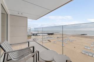 Op de zesde verdieping van residentie Milenka bevindt zich dit stijlvol 3-slaapkamerappartement van 111 m², aangevuld met een ruim terras van 18 m². Een zeldzame kans om te wonen op een toplocatie in Het Zoute, waar architectuur en uitzicht samenkomen in een harmonie van rust en verfijning.<br />De Skyframe raampartijen zorgen voor een panoramisch zicht op zee en laten het natuurlijke licht overvloedig binnenstromen. De open keuken met Miele toestellen, Travertin werkblad en walnoot kastdeuren vormt het hart van de leefruimte – een plek waar esthetiek en functionaliteit elkaar versterken.<br /><br />Elke slaapkamer is ontworpen met oog voor privacy en comfort. Twee hebben een ensuite badkamer, de derde een badkamer aan de overzijde van de palier. Een apart toilet en een bijkeuken met was- en droogkast bieden extra gemak.<br />De afwerking is uitzonderlijk: ingefreesde stopcontacten, ledverlichting in maatkasten, subtiele rondingen in natuursteen en schrijnwerk – elk detail draagt bij aan een tijdloze woonbeleving. Dit appartement is ideaal voor wie op zoek is naar discrete luxe en een kwalitatieve levensstijl aan zee.<br /><br />👉 Verkoop onder registratierechten.